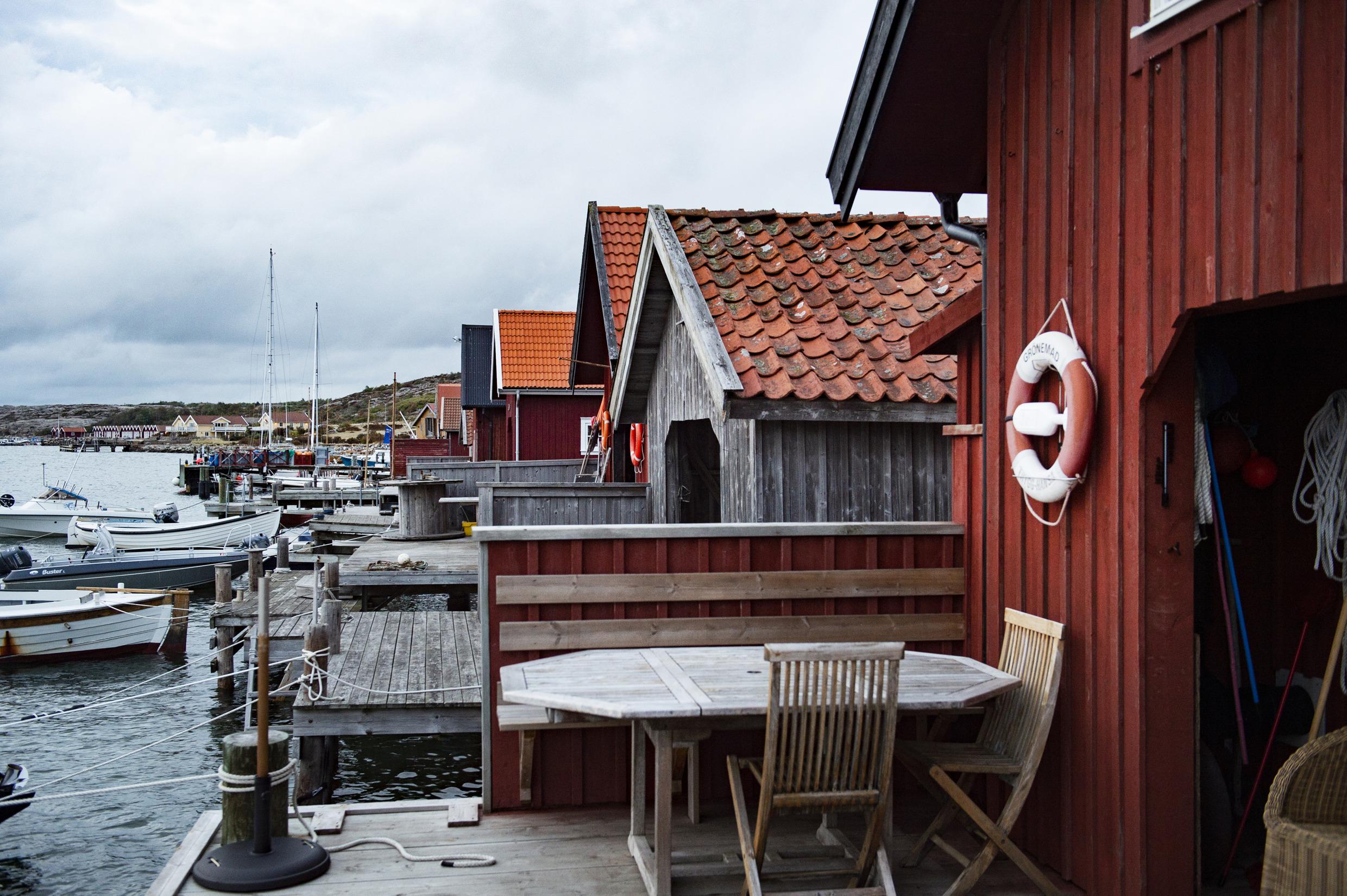 Several wooden fishermen's huts along the sea and boats anchored by them.