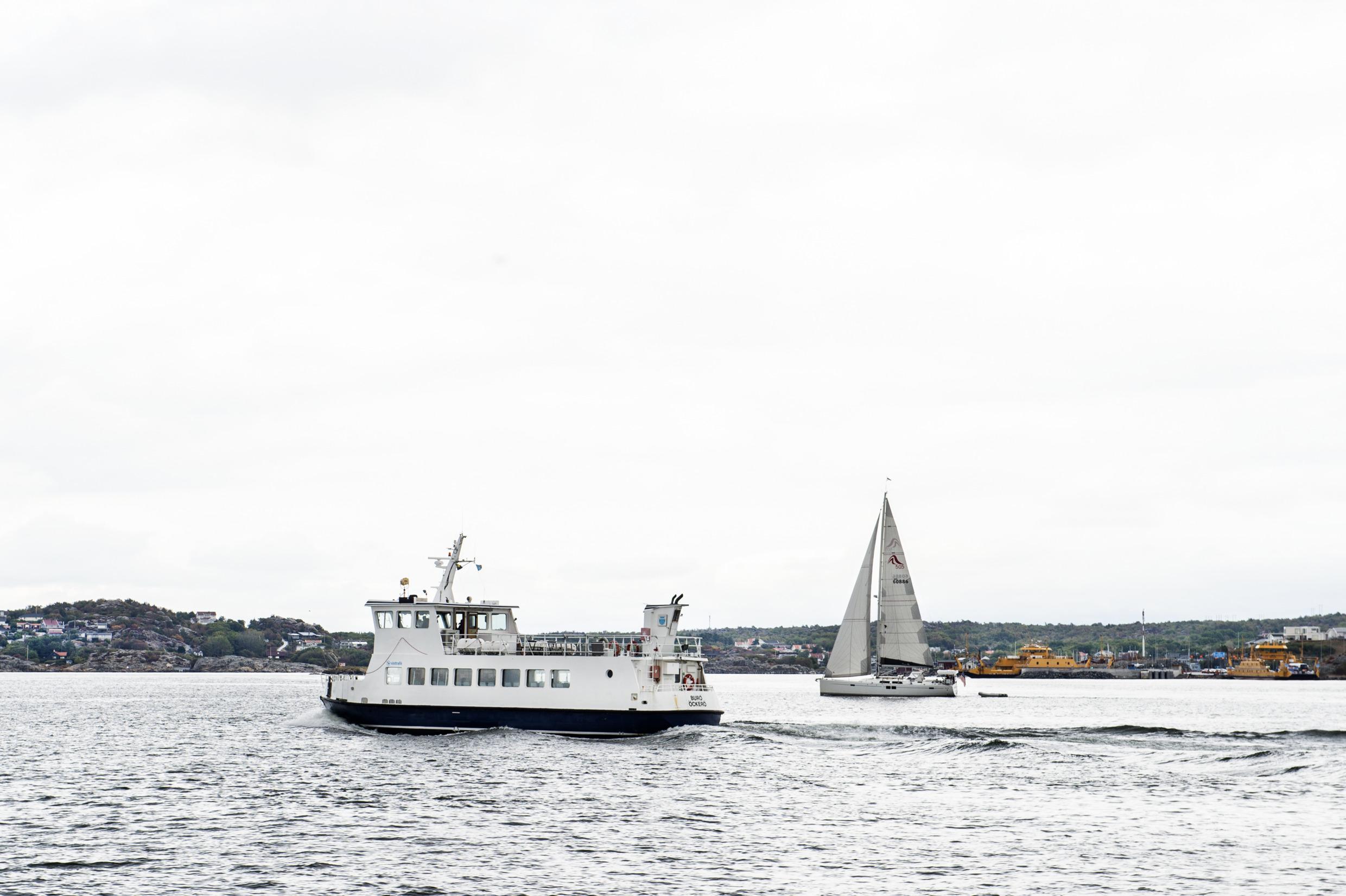 Eine kleine Fähre und ein Segelboot auf dem Meer bei einer Insel vor Göteborg.
