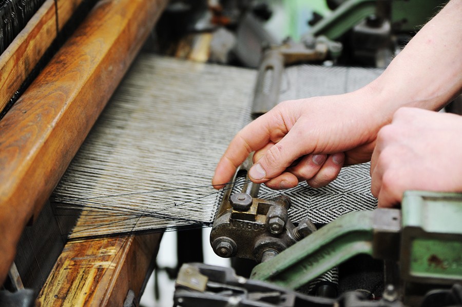Close-up of hands working with threads on a weaving loom at Växbo Lin in Hälsingland.