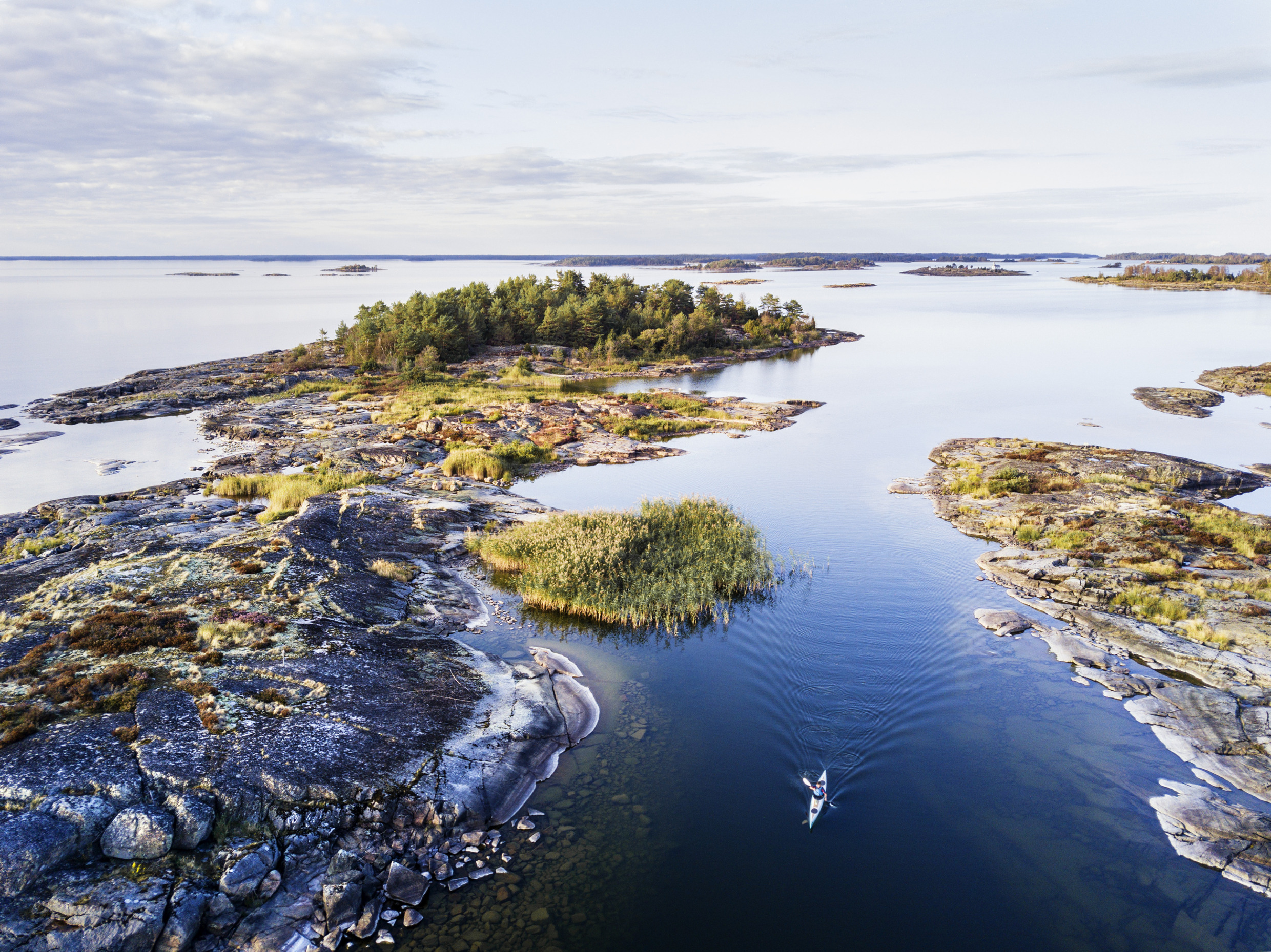 A person kayaking between small islands in lake Vänern during summer.