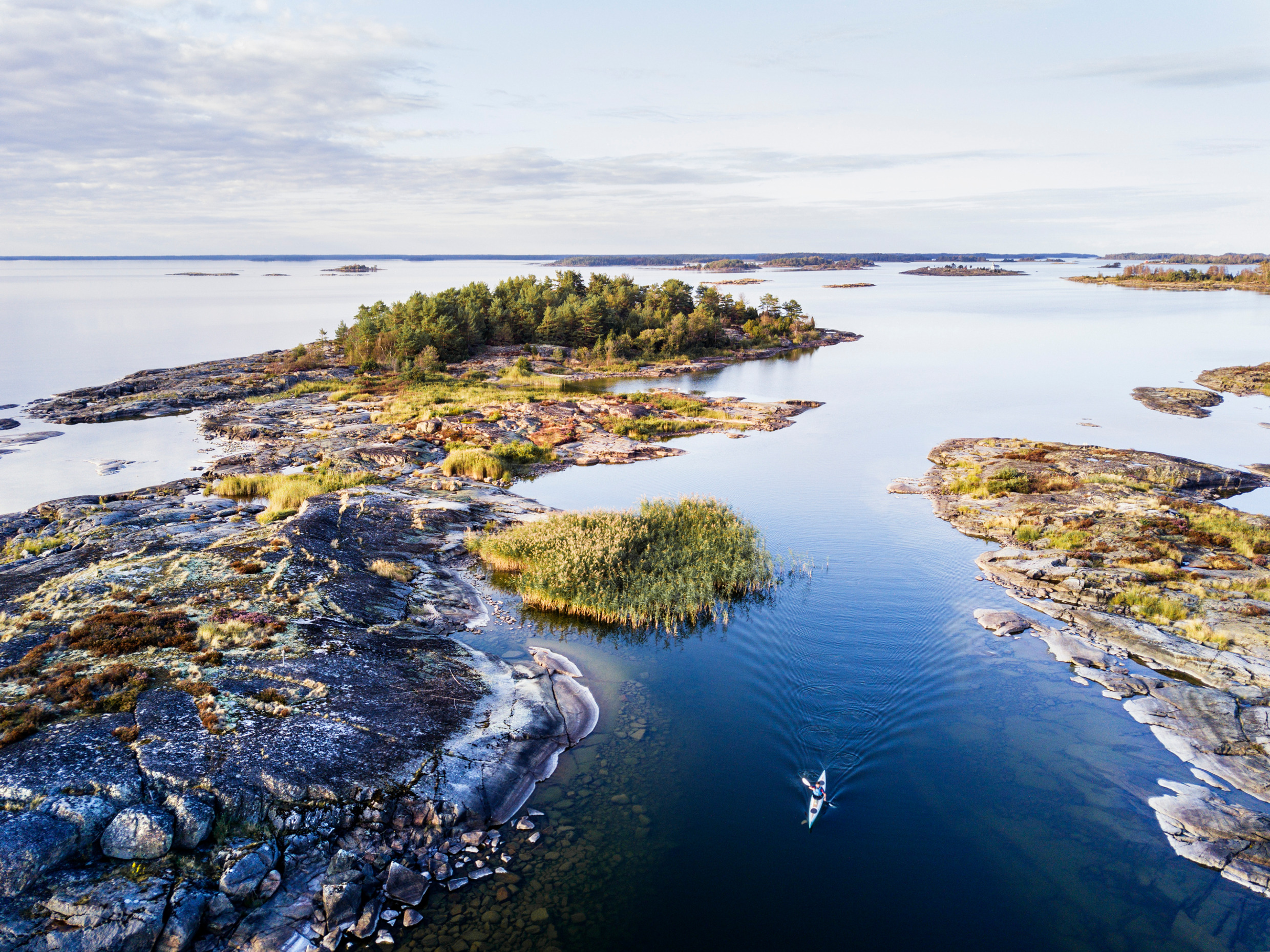 A person kayaking between small islands in lake Vänern during summer.
