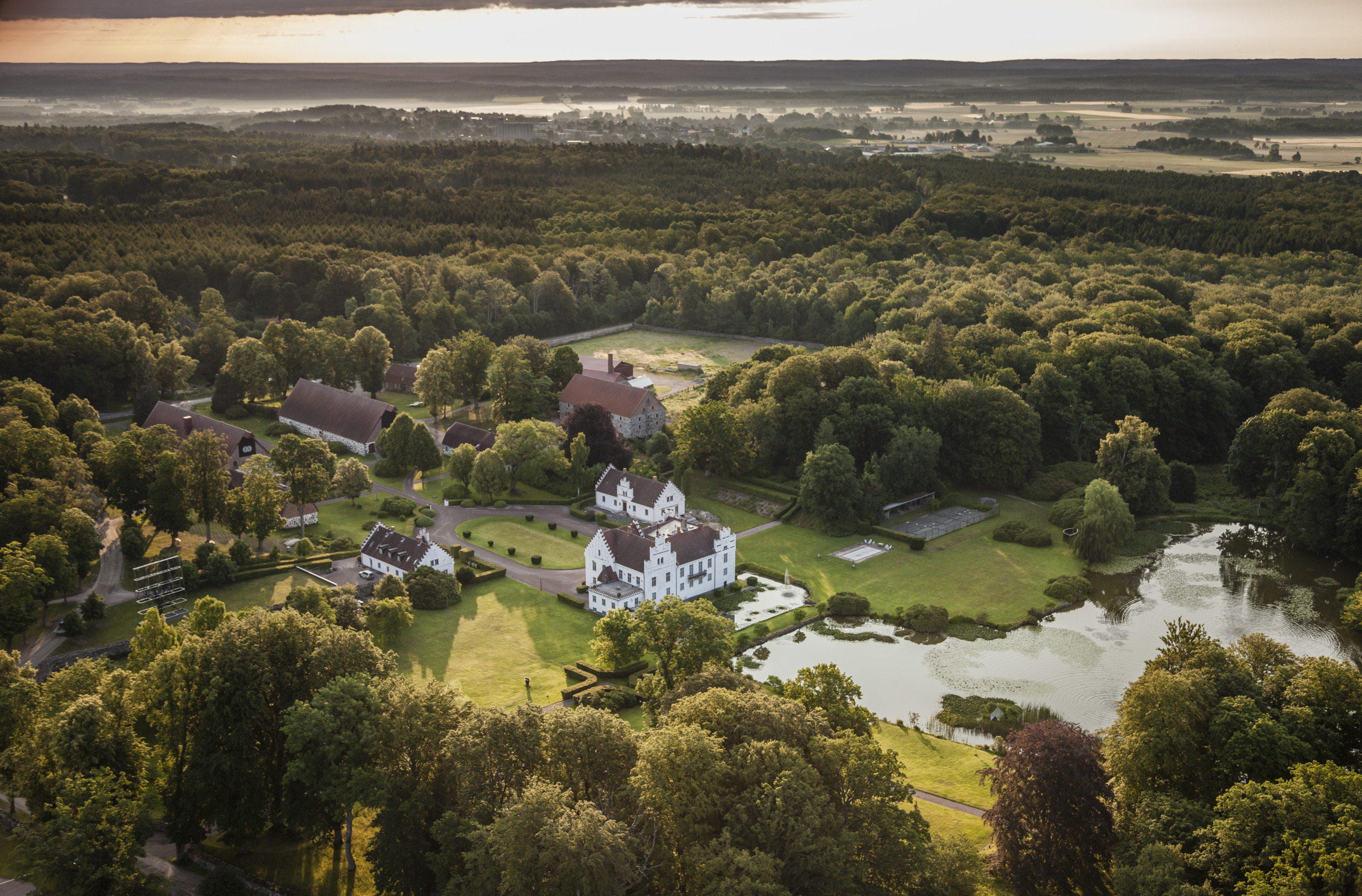 Aerial view of Wanås Konst in Skåne, Sweden, showing the historic estate surrounded by lush forest, ponds and open landscape.