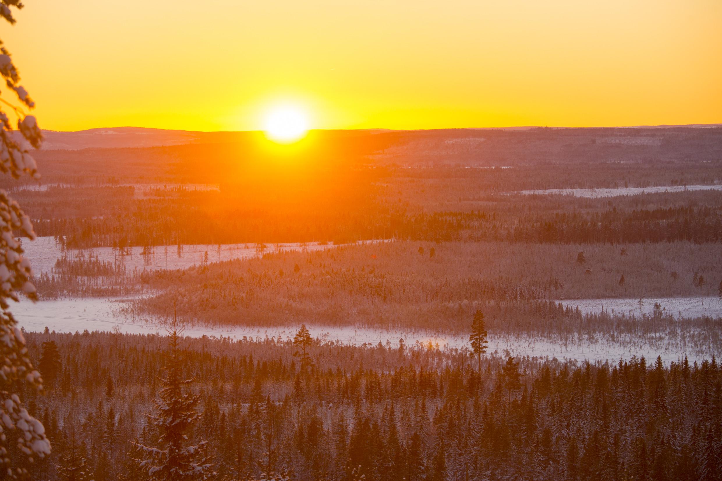 Ondergaande zon boven een winterlandschap.