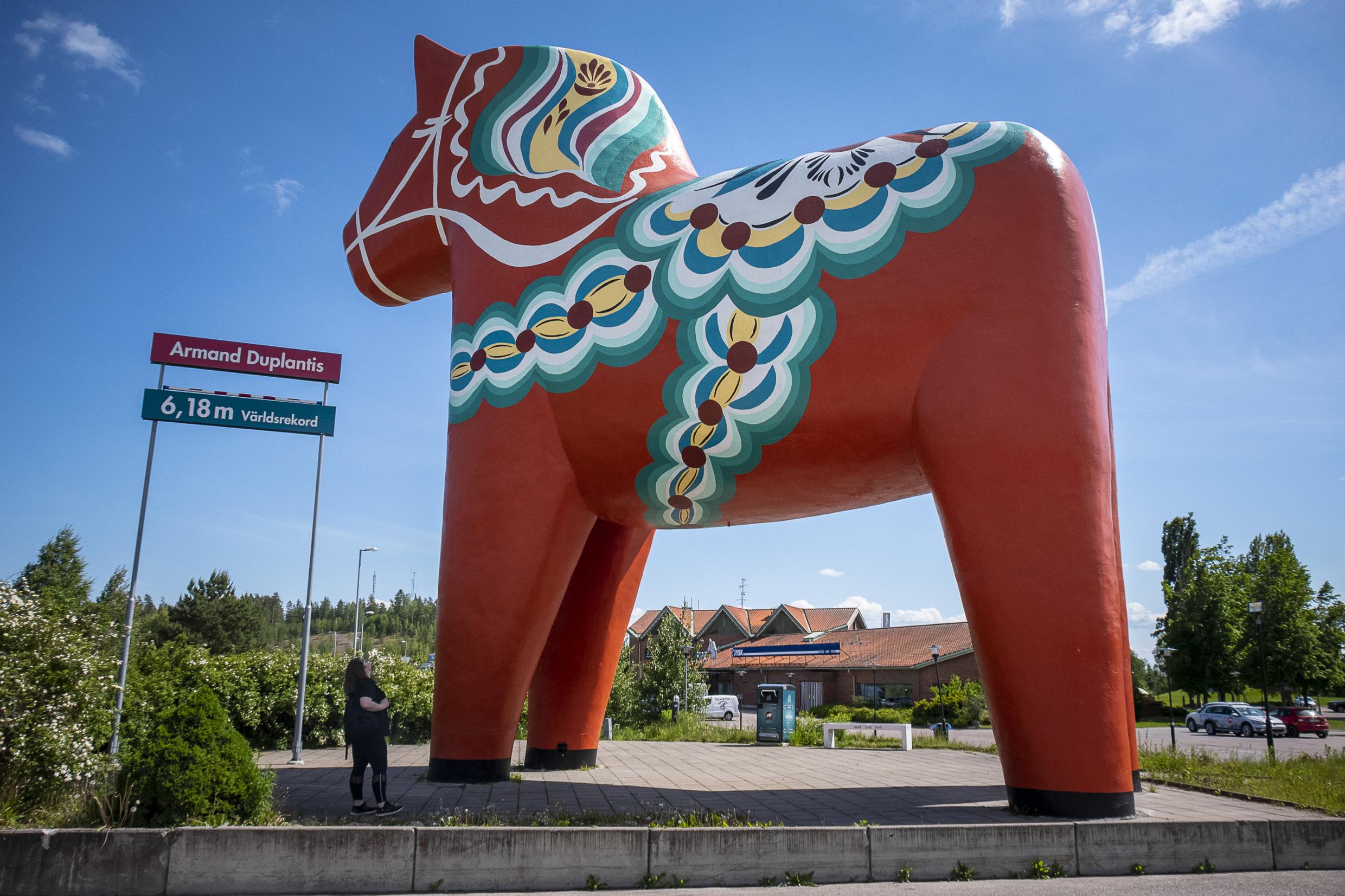A woman looking up on the world’s largest Dala horse.