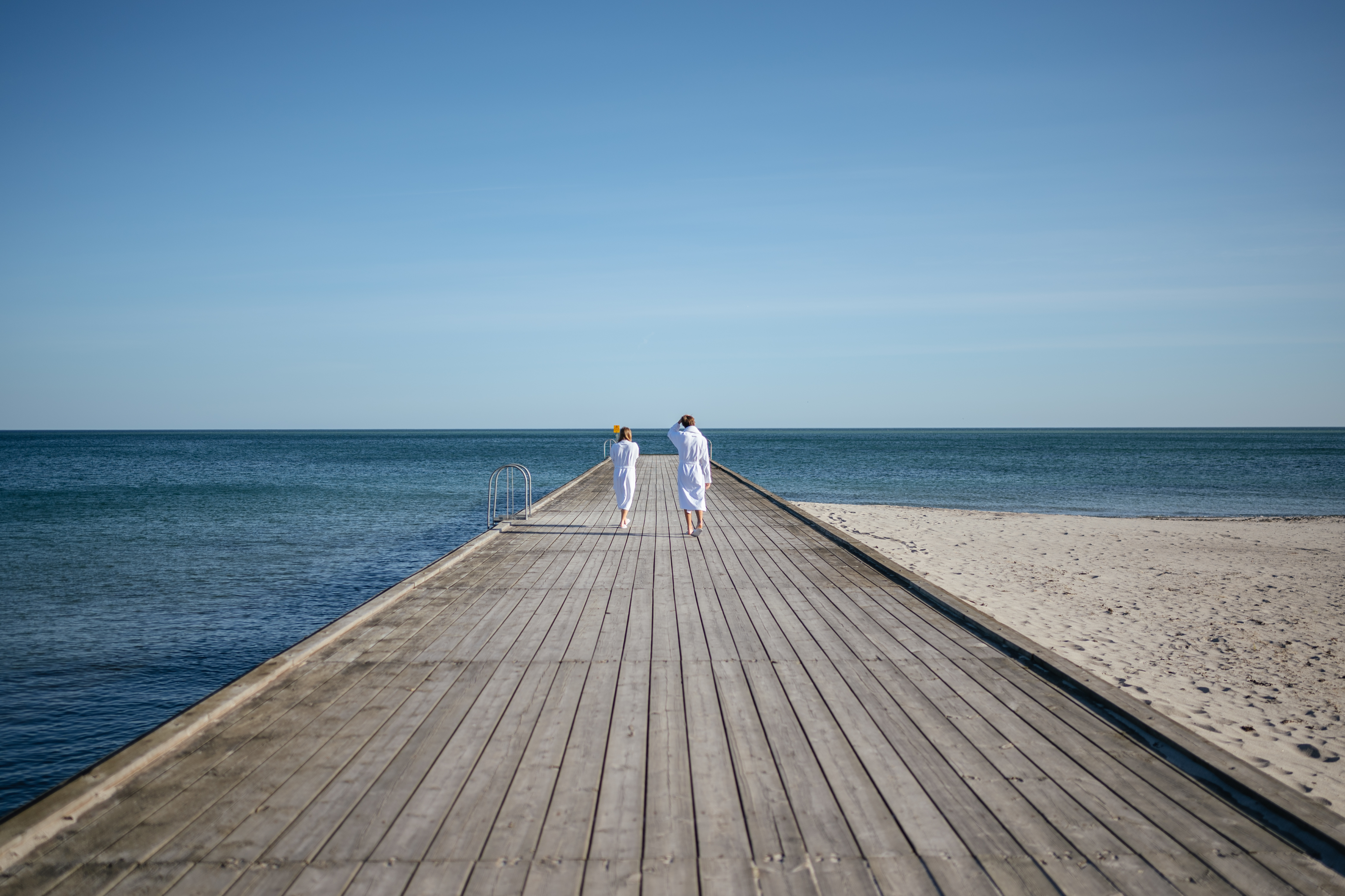Twee mensen op een pier met uitzicht op zee.