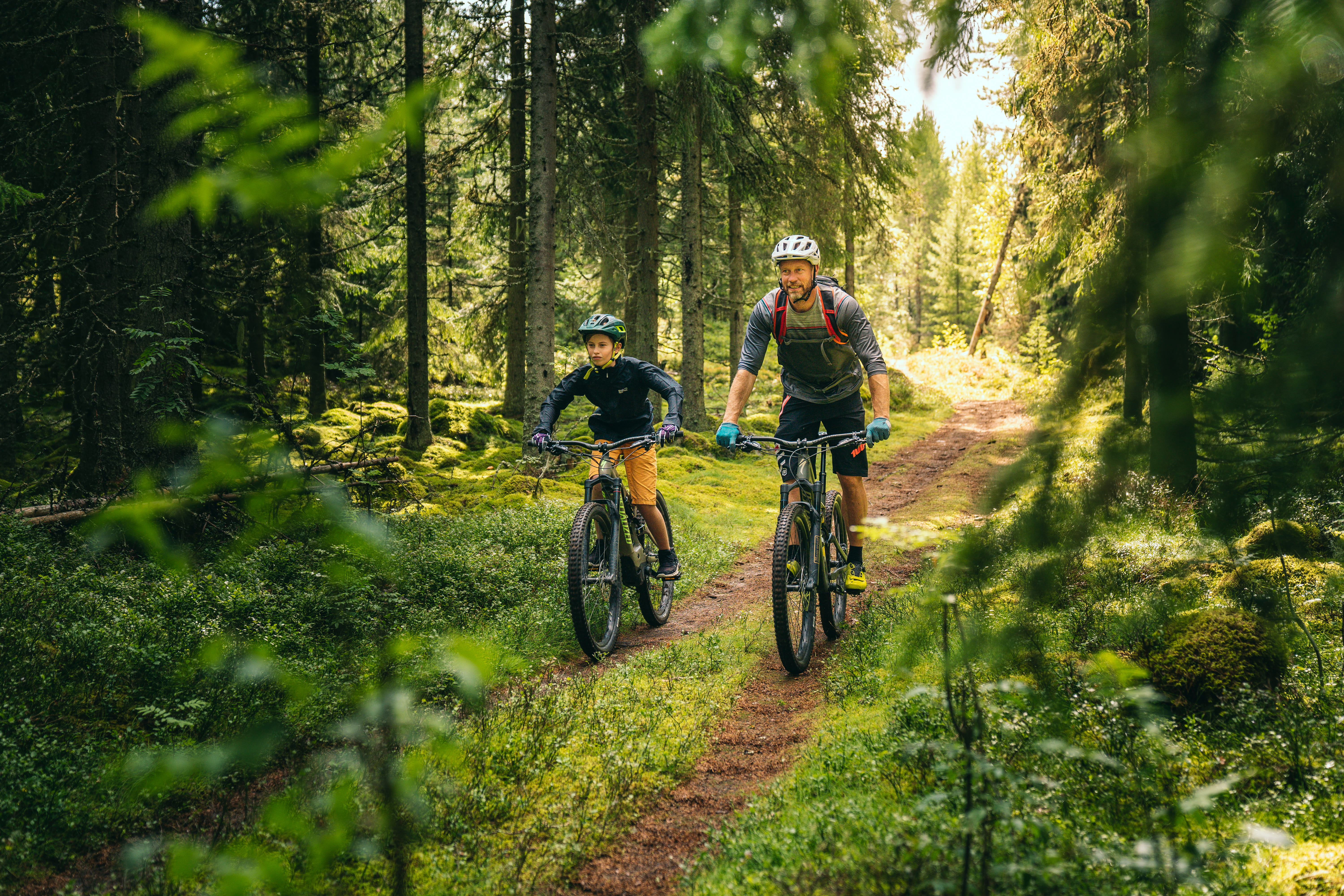 Two persons biking in the forest.