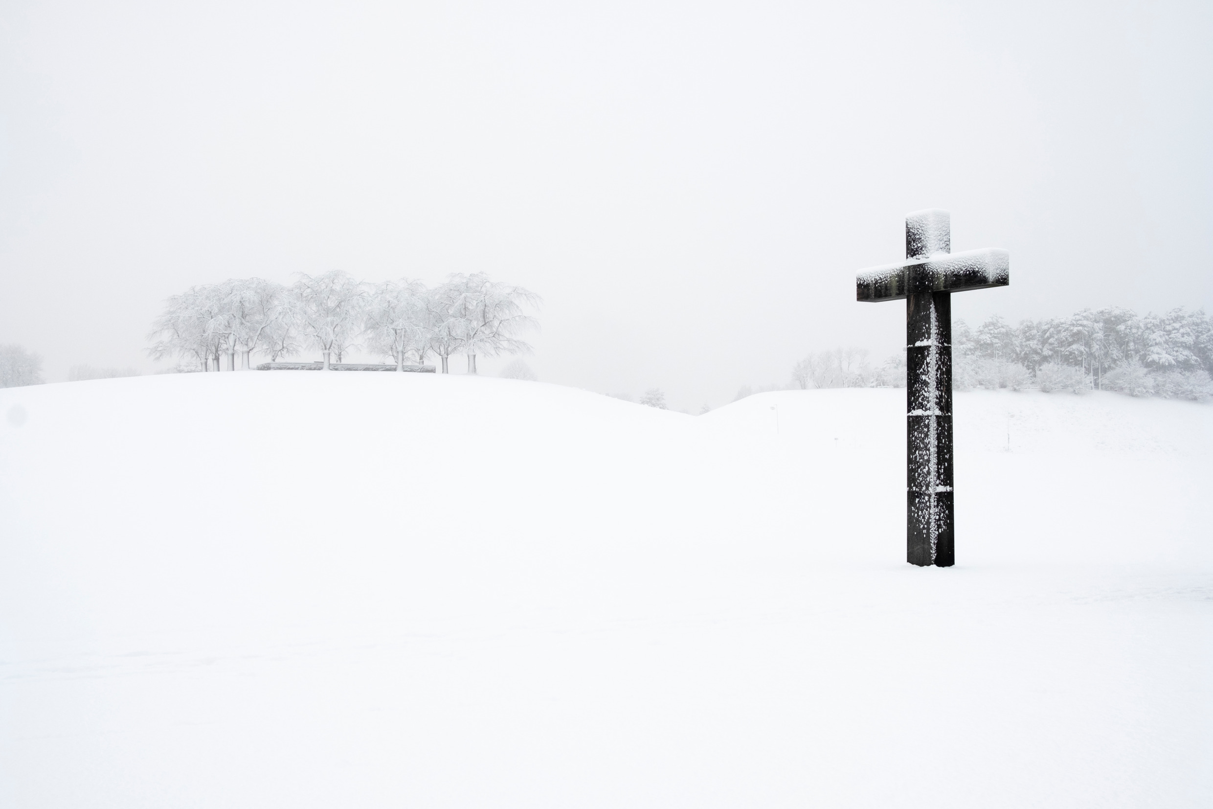 A snow-covered landscape with a large cross in the foreground.