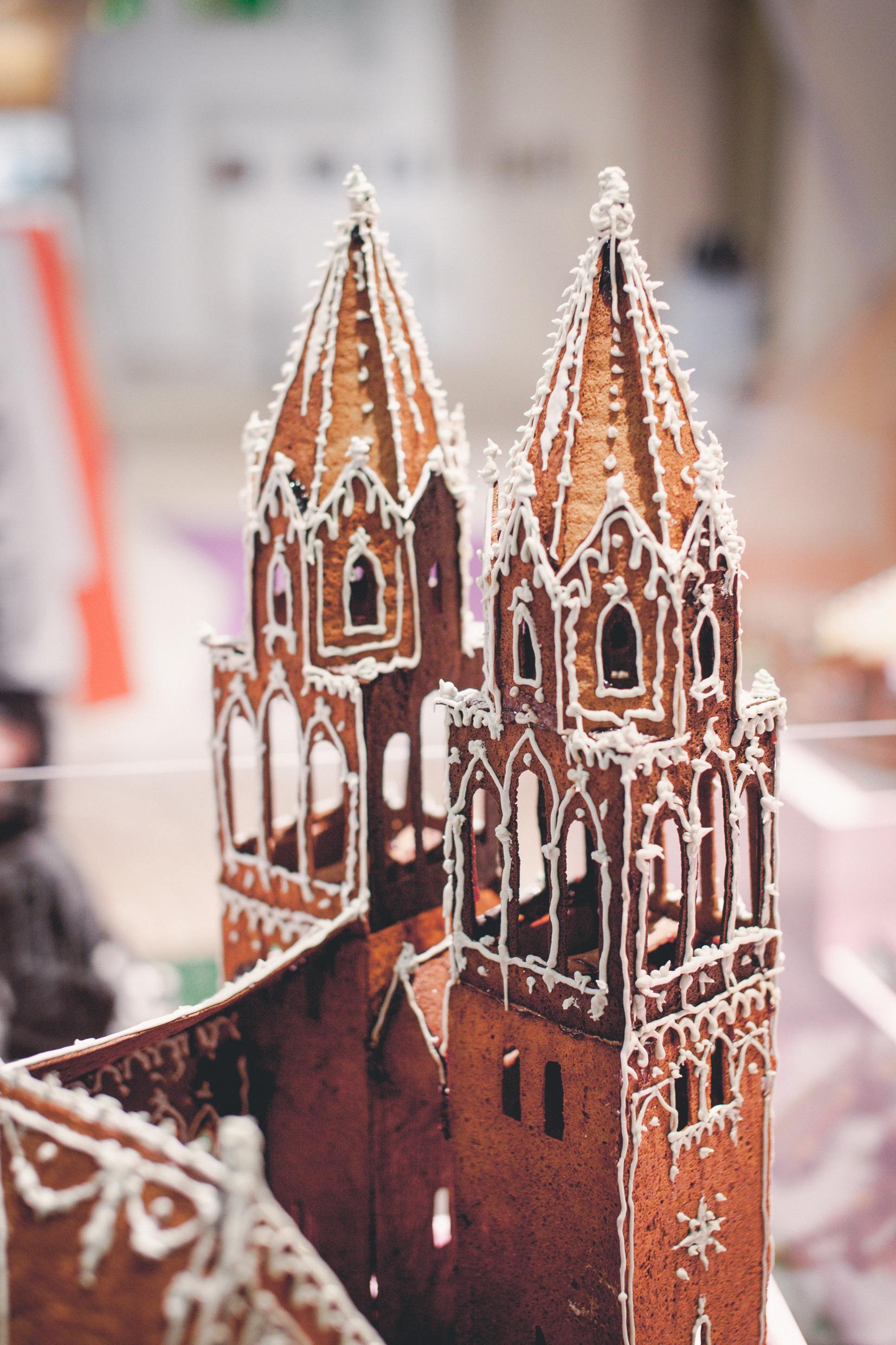 Een close-up van een peperkoekhuisje in de vorm van een kasteel, met 2 torens en witte glazuurversiering.