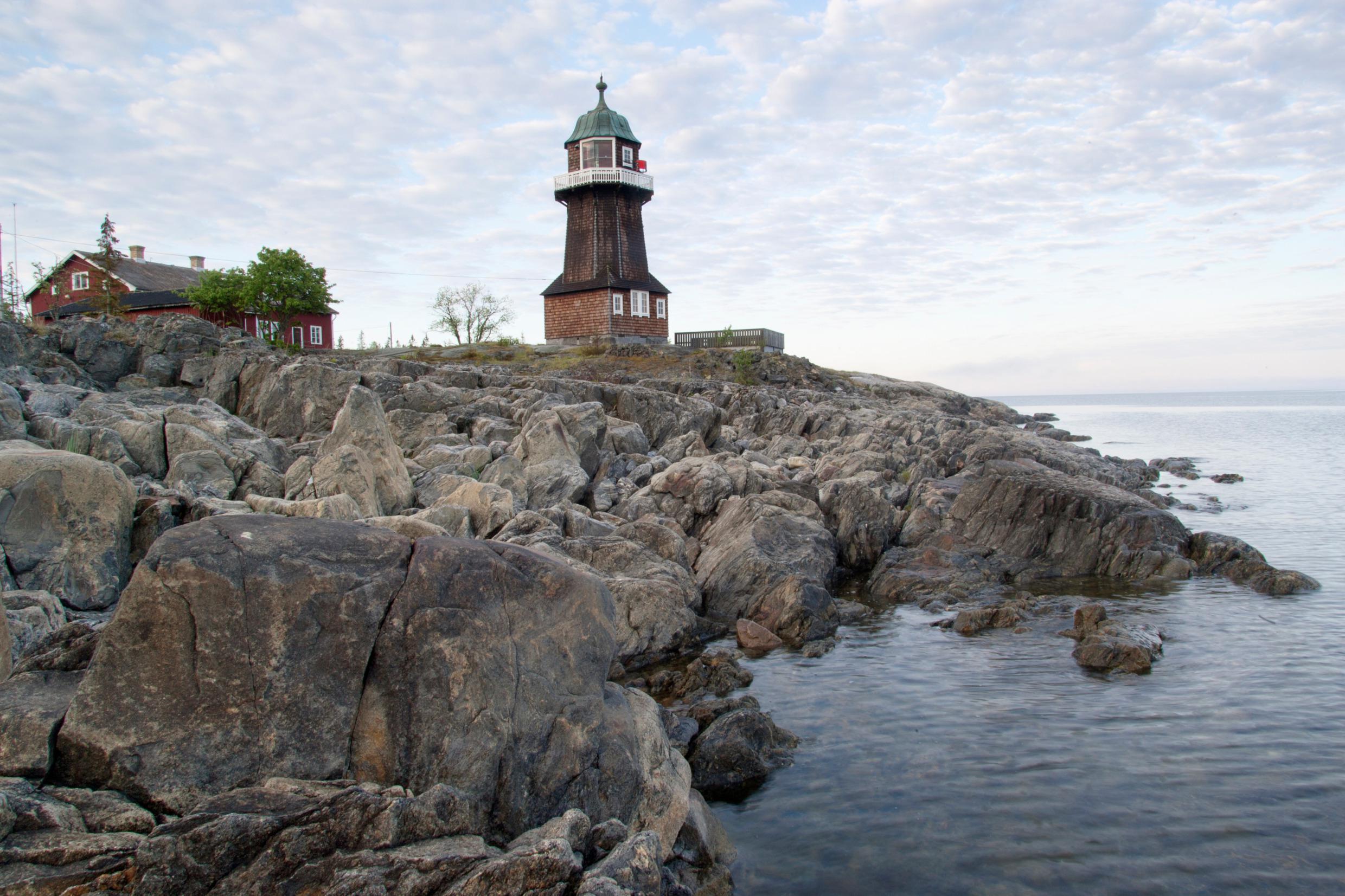 The lighthouse on Holmön overlooking the rocky shoreline beside Berguddens Fyrvaktarbostäder.