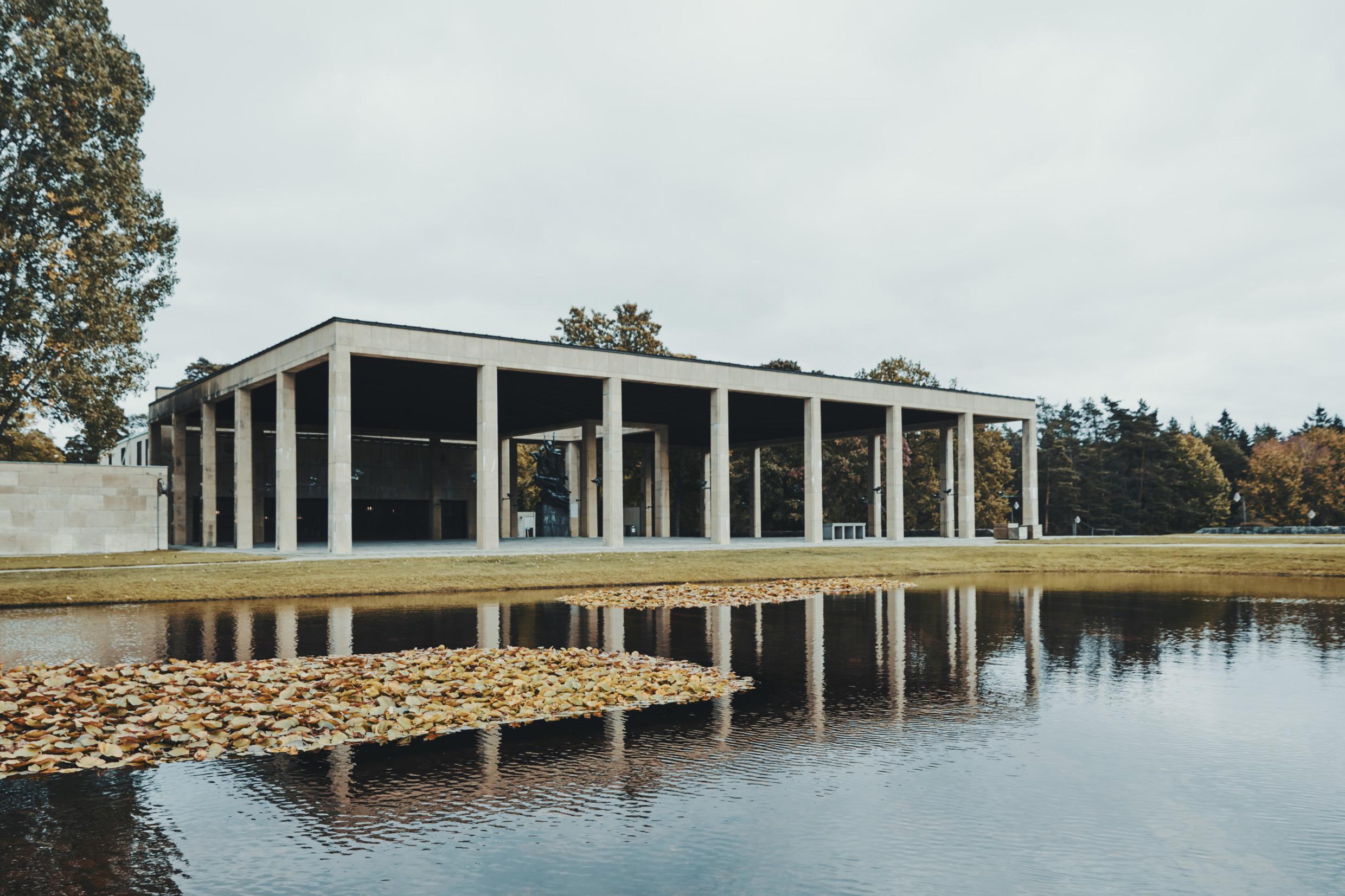 Ein Gebäude und ein Teich auf dem Friedhof Skogskyrkogården in Stockholm.