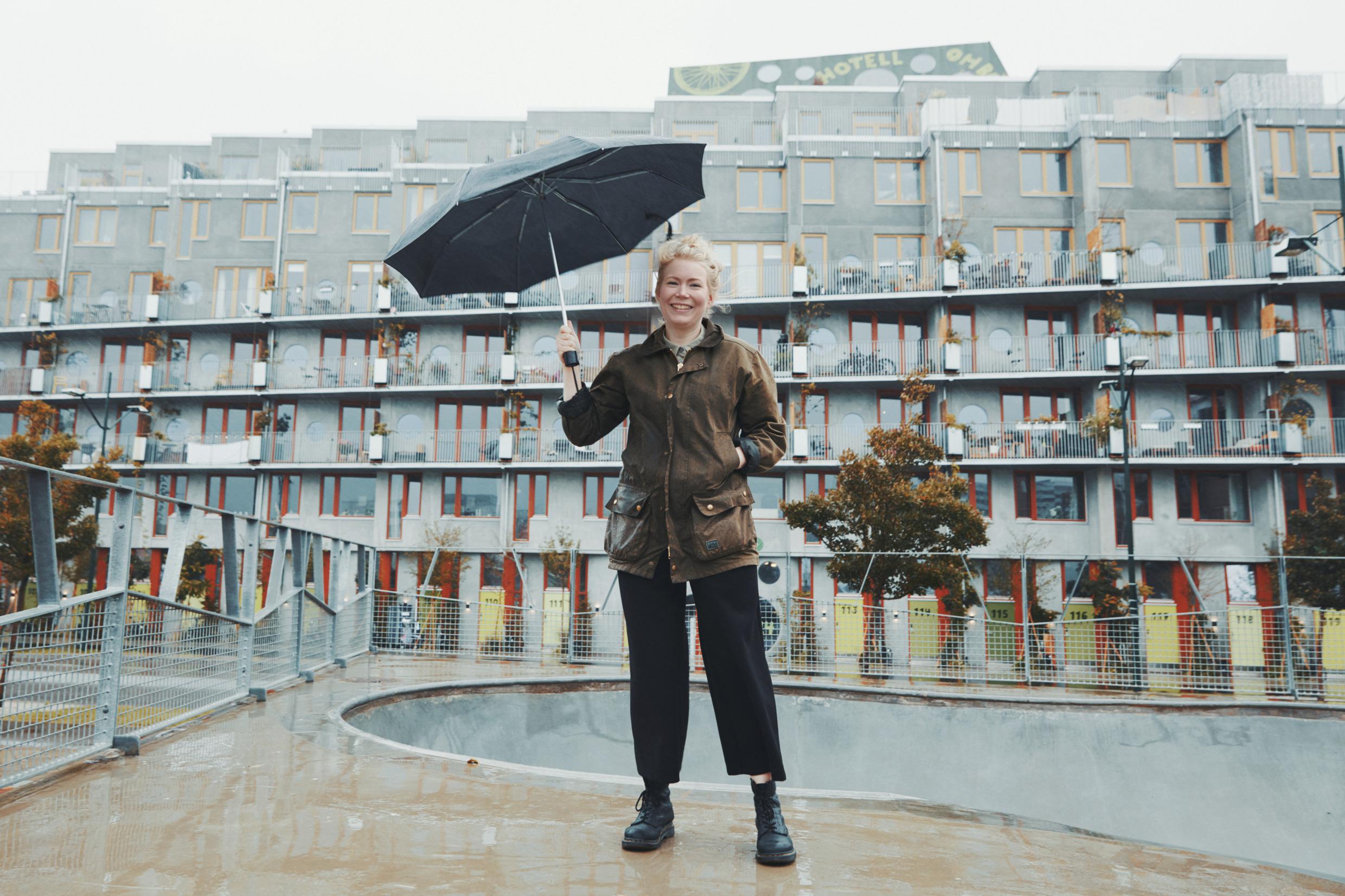 A woman holds an umbrella by a pool outside Ohboy Hotel.