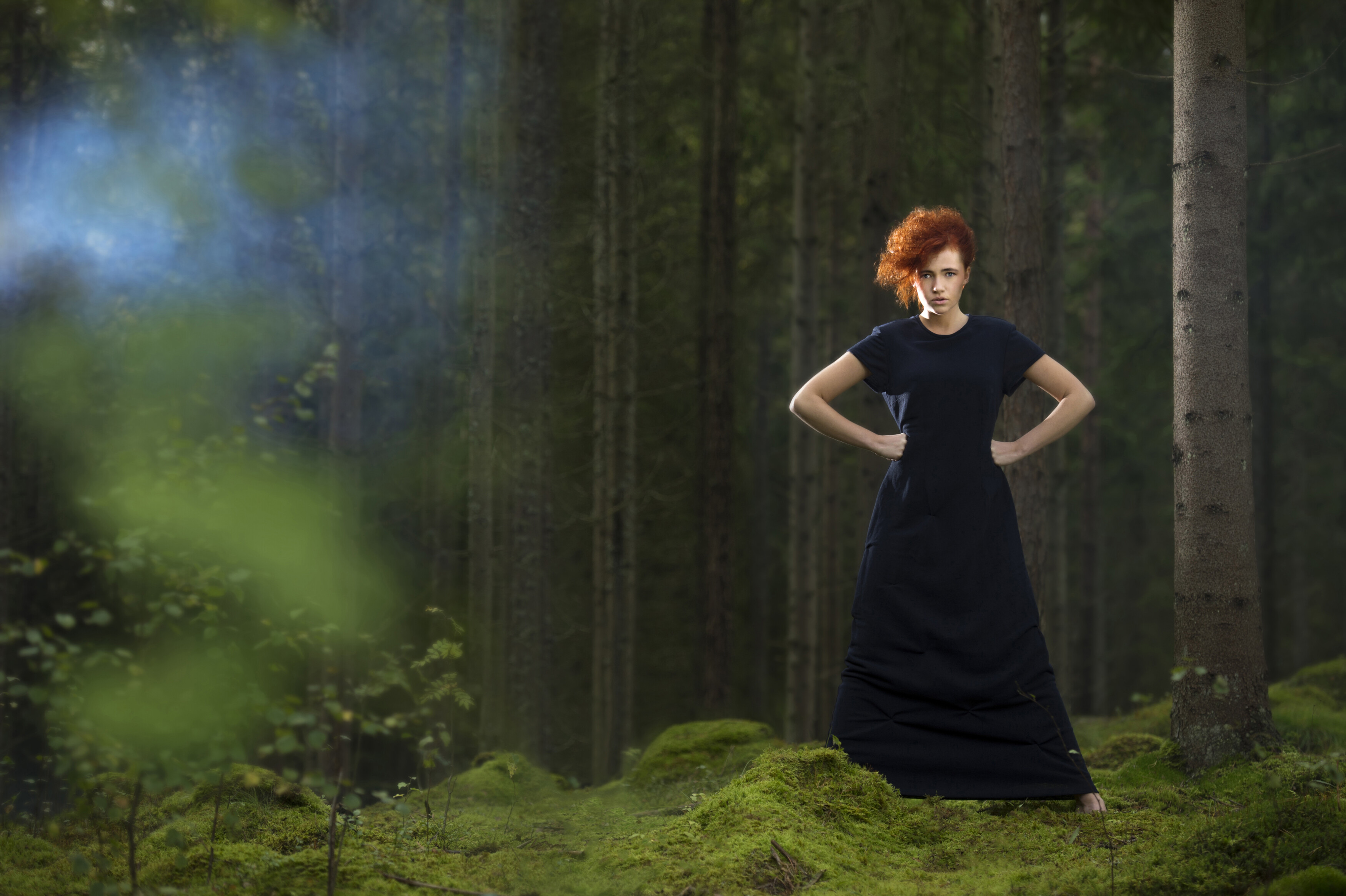 A person wearing a dress standing in the forest.