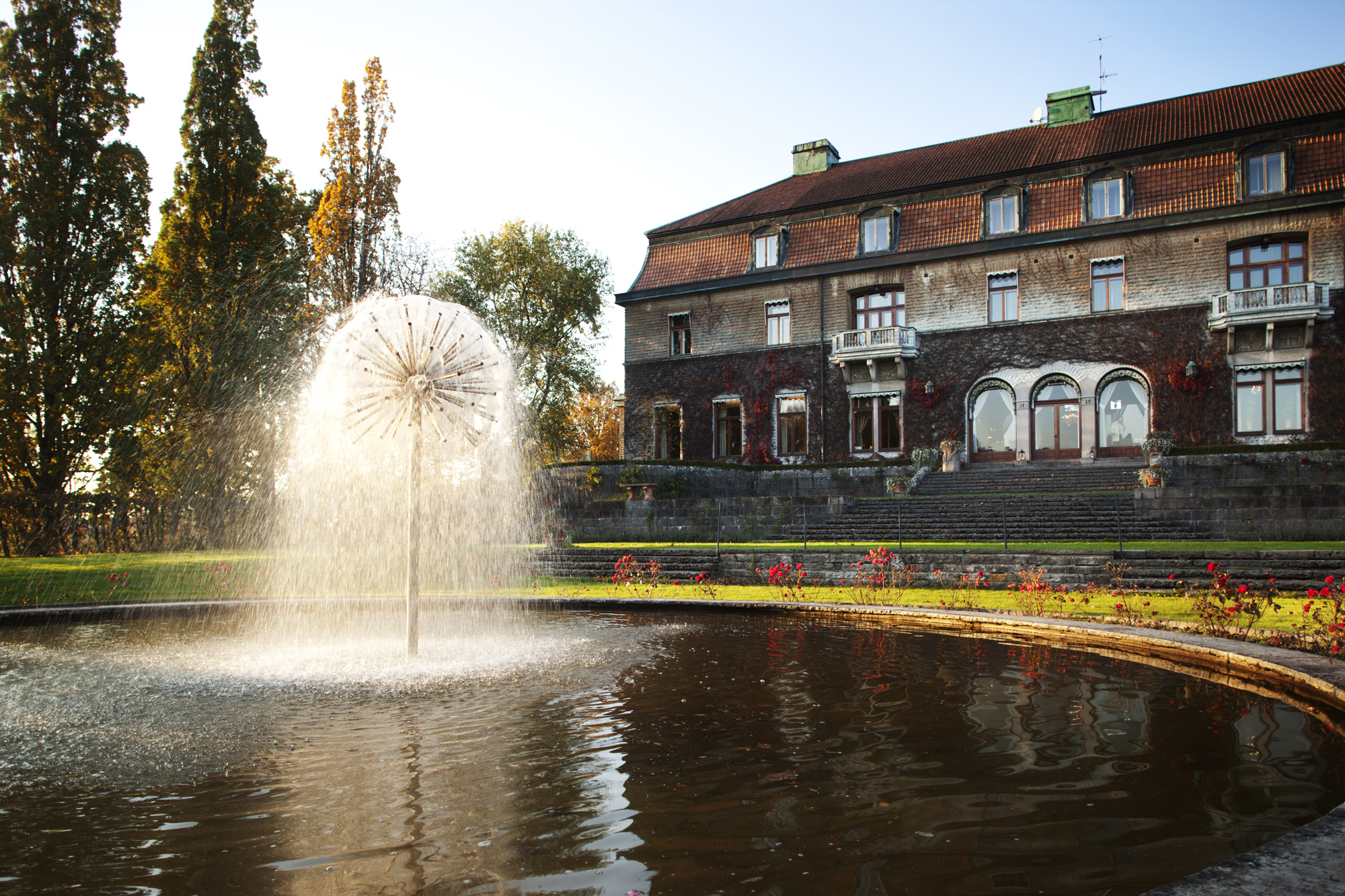 Une fontaine devant un grand bâtiment en automne.