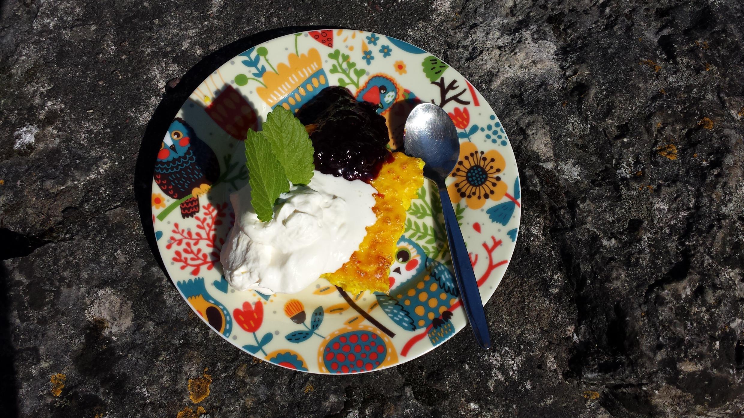 A colourful plate with saffron pancake, cream and jam.