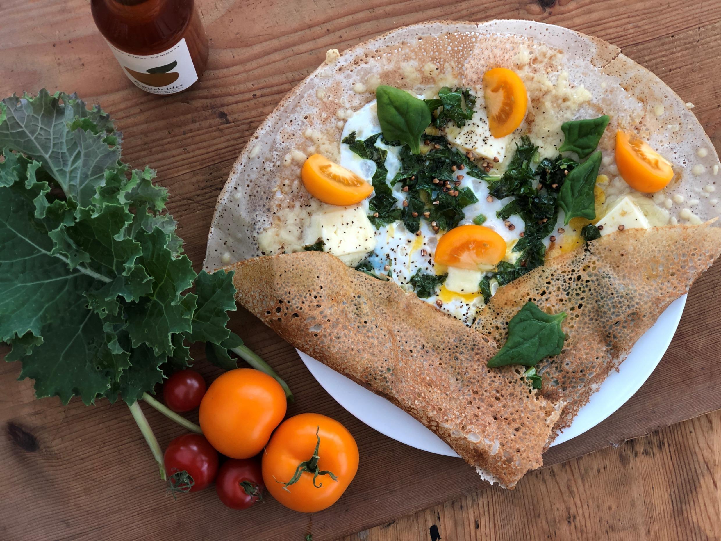 Close-up of a hearty galette with kale, egg and tomatoes, served on a plate at Järvsö Crêperie.