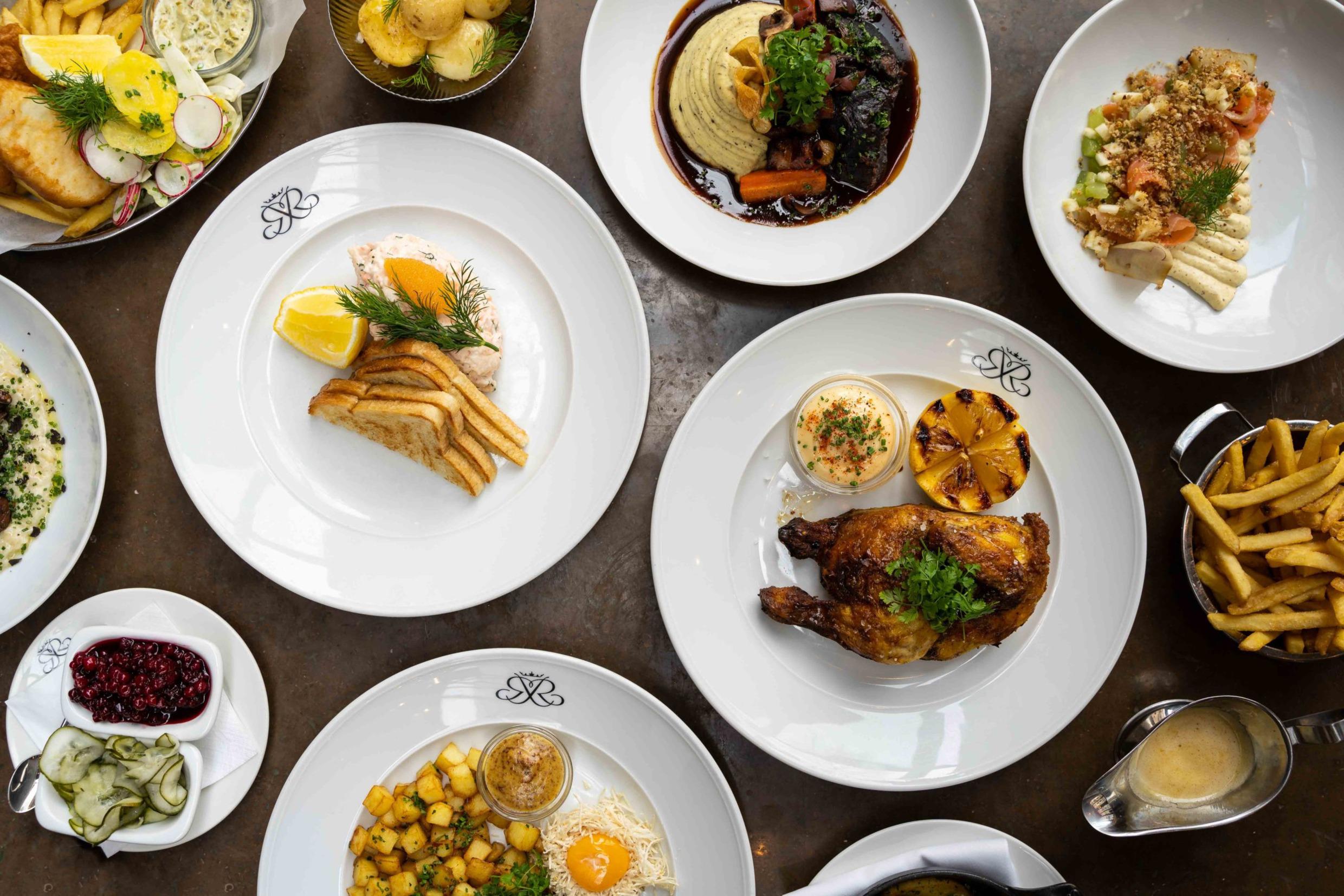 Een tafel met borden met netjes geplaatste etenswaren zoals toast skagen, een toast met garnalen en kaviaar..