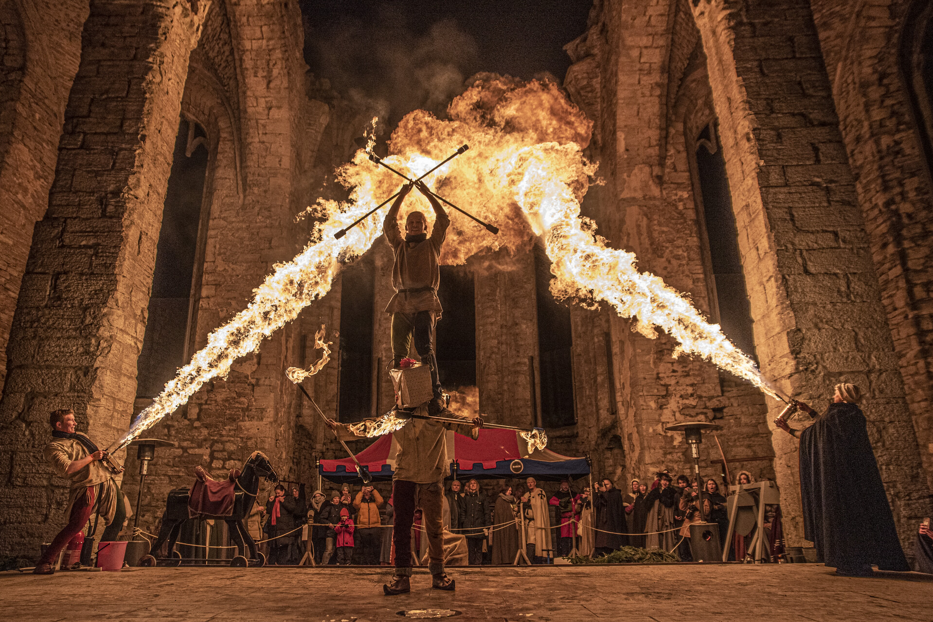 Des artistes pyrotechniques en costume médiéval divertissent la foule à l'intérieur d'une église en ruines du XIIIe siècle pendant le Noël médiéval à Visby.