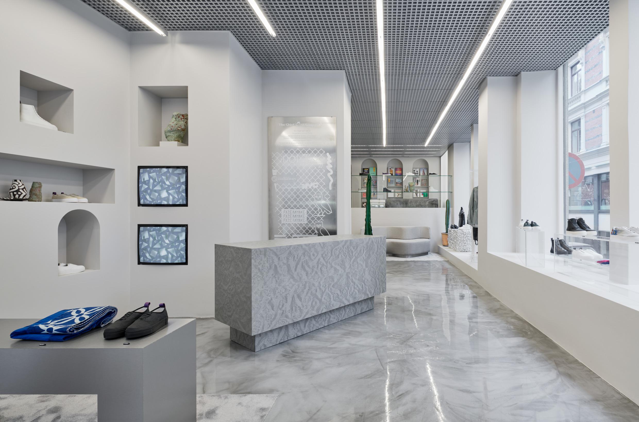 A minimalistic bright shop, with marble floor. Sneakers and a few other items on display.