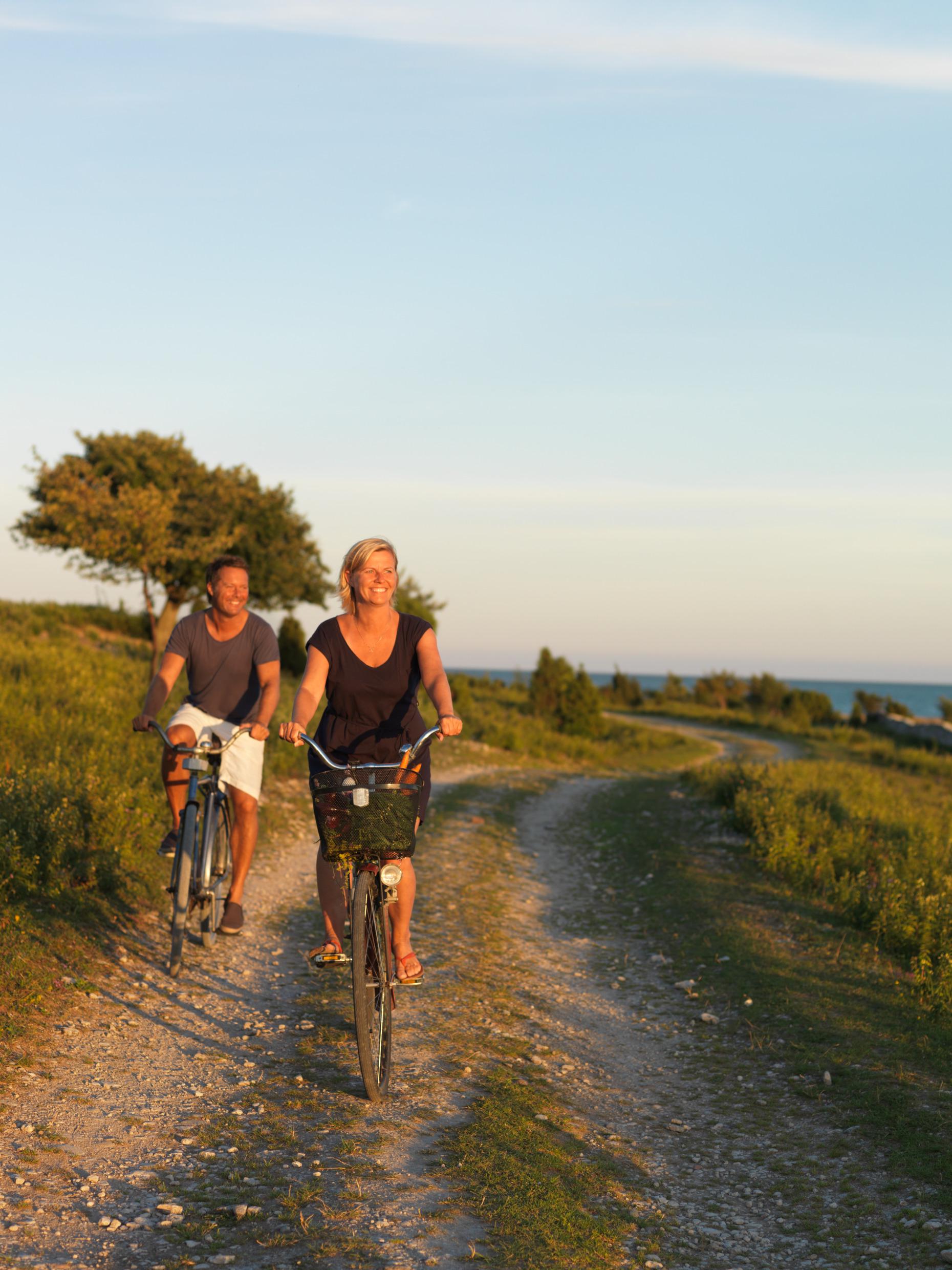 Eine Frau und ein Mann radeln auf einem Schotterweg entlang der Küste der Insel Fårö.