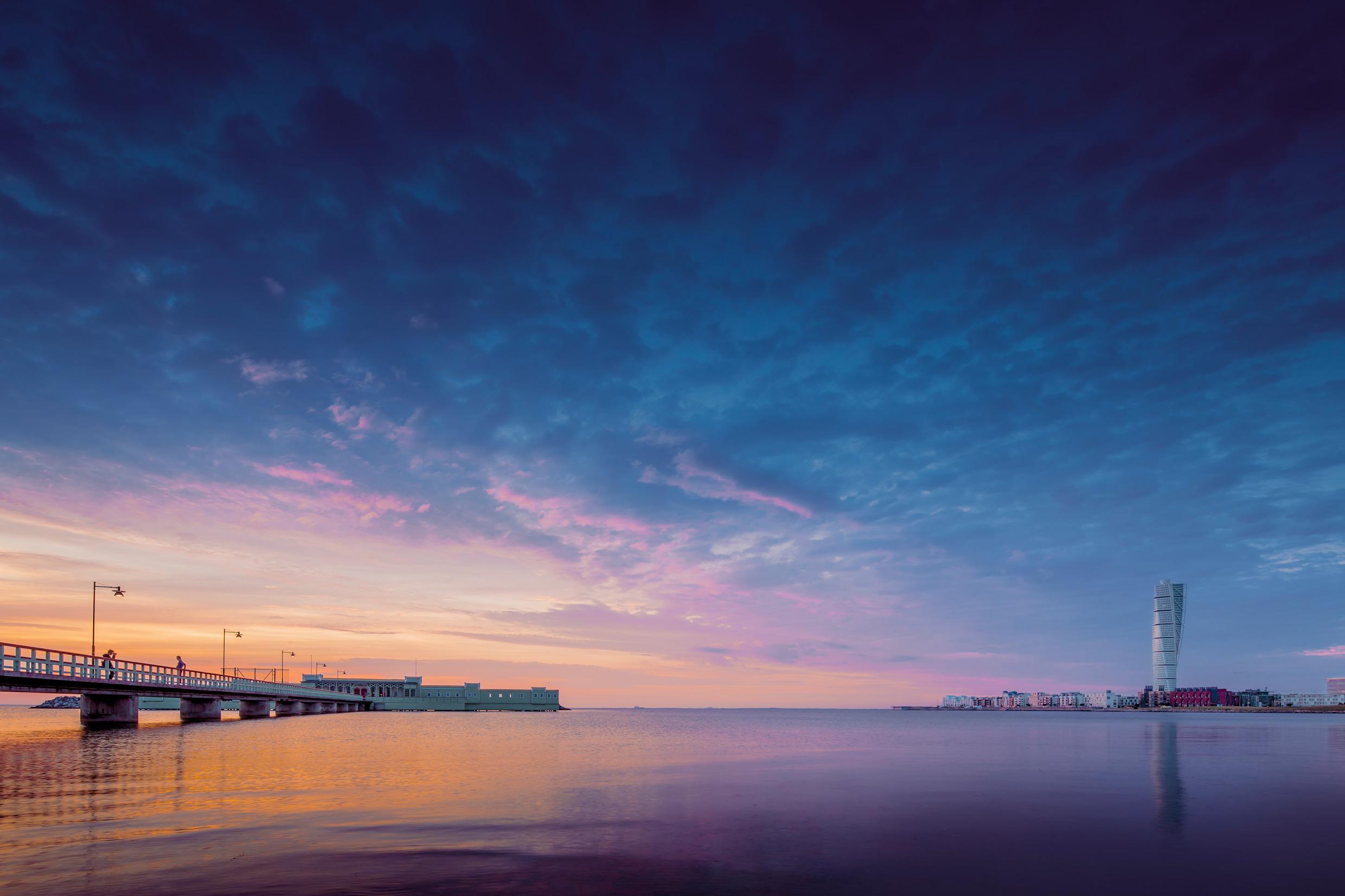 Evening view of a jetty leading out to a cold bath house. On the horizon you see Turning Torso.