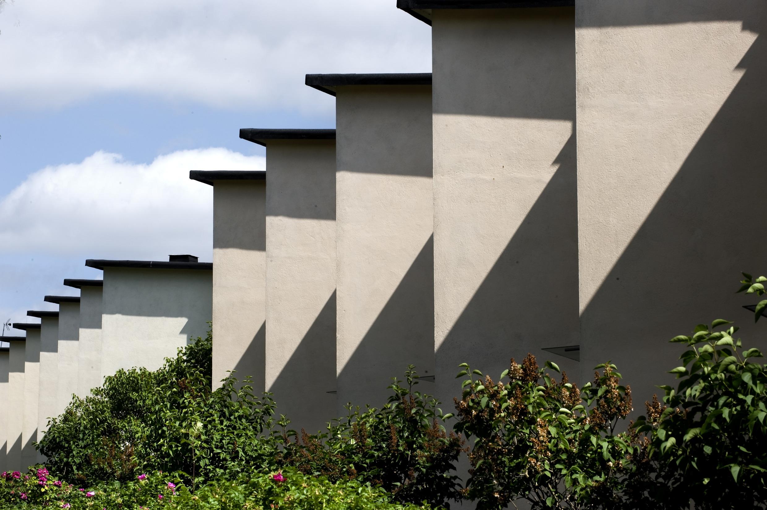 Several white terraced houses with flat black roof, from the functionalism era, seen from the side.