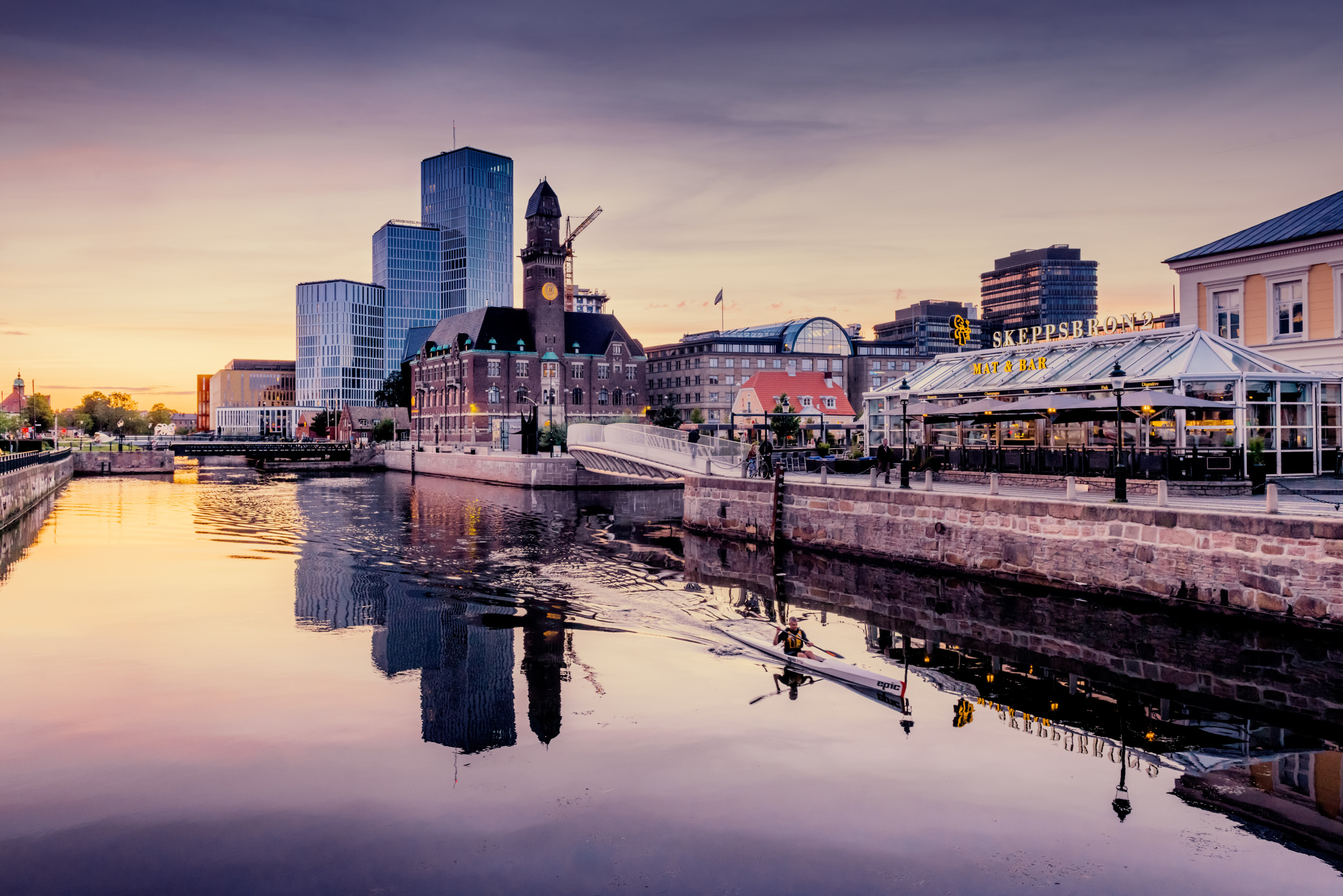 Een persoon die bij zonsopgang in het kanaal in Malmö kanoën.