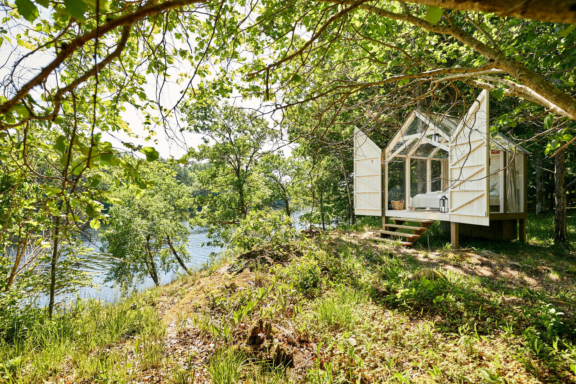 Eine Hütte aus Holz und Glas in der Natur während des Sommers.