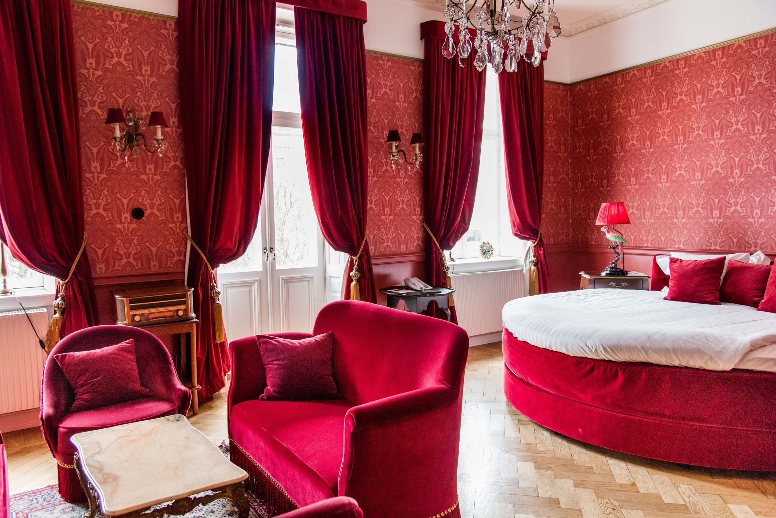 Hotelkamer in Hotel Eggers met dieprode muren, rode fluwelen gordijnen en bijpassend meubilair.