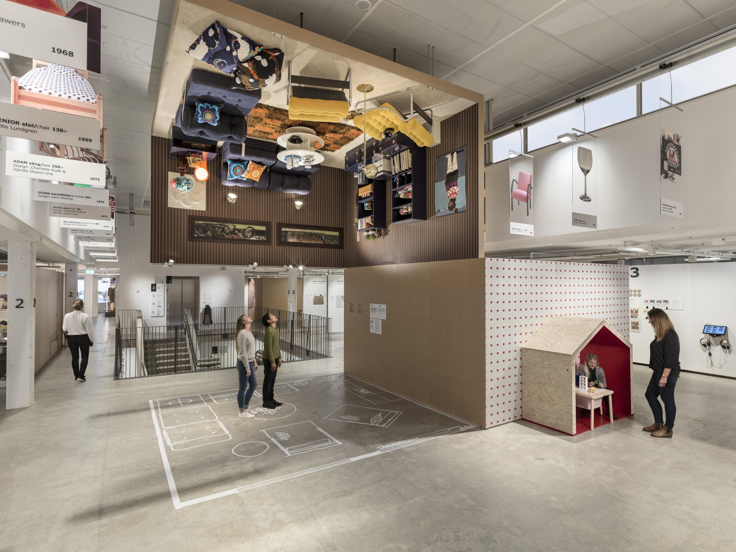 Visitors at the IKEA museum viewing an exhibition with an upside down room in the cieling.