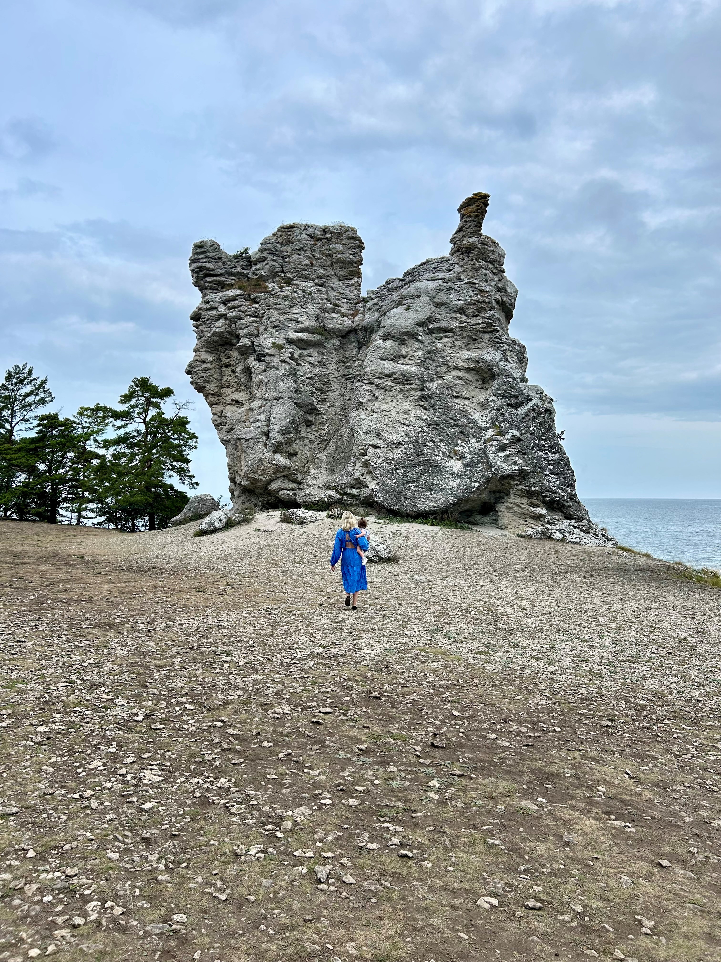 A person walking towards a large limestone sea stack by the coast on Gotland, with the sea visible in the background.