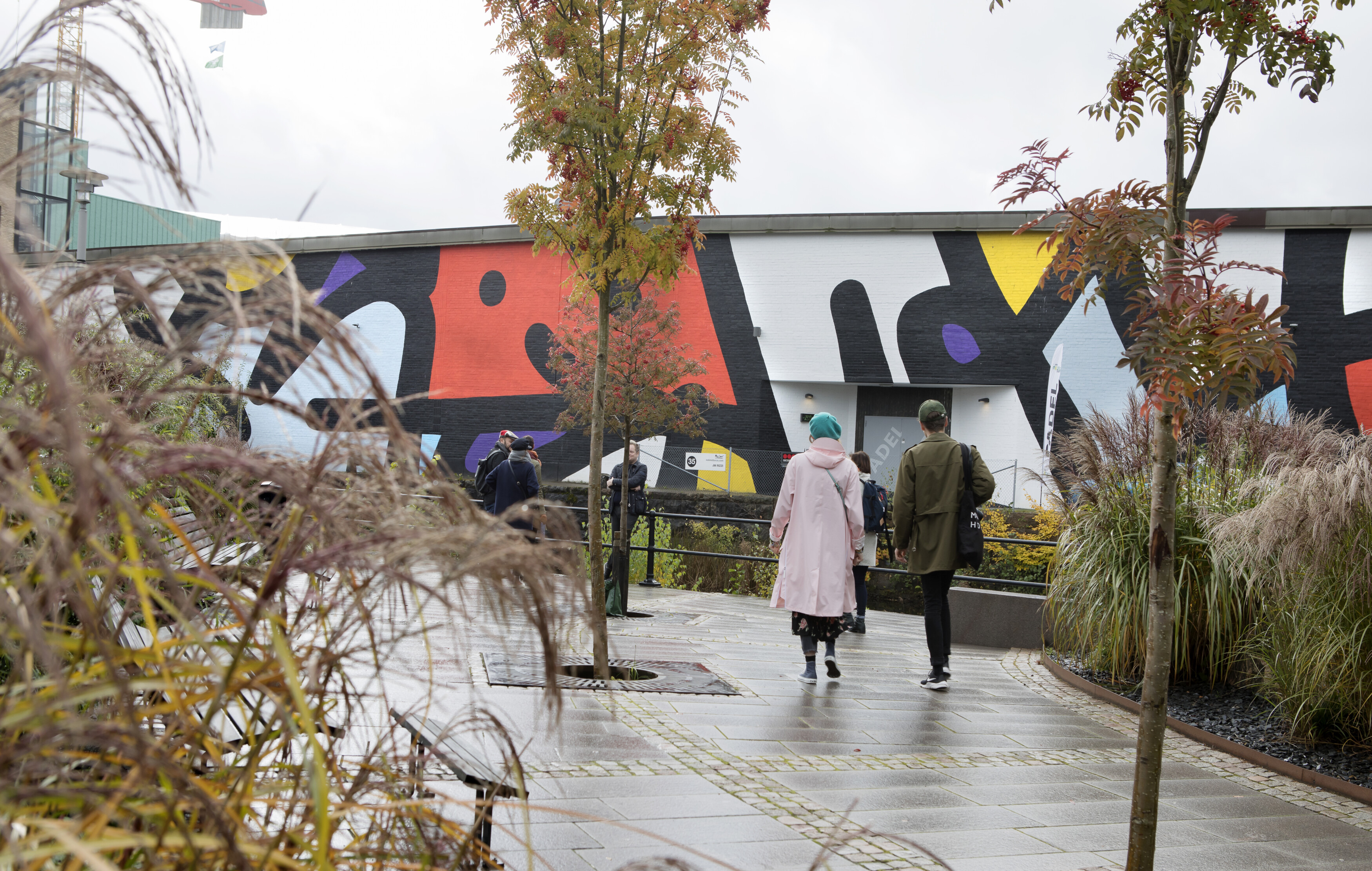 Two people walking in front om street art in the rain