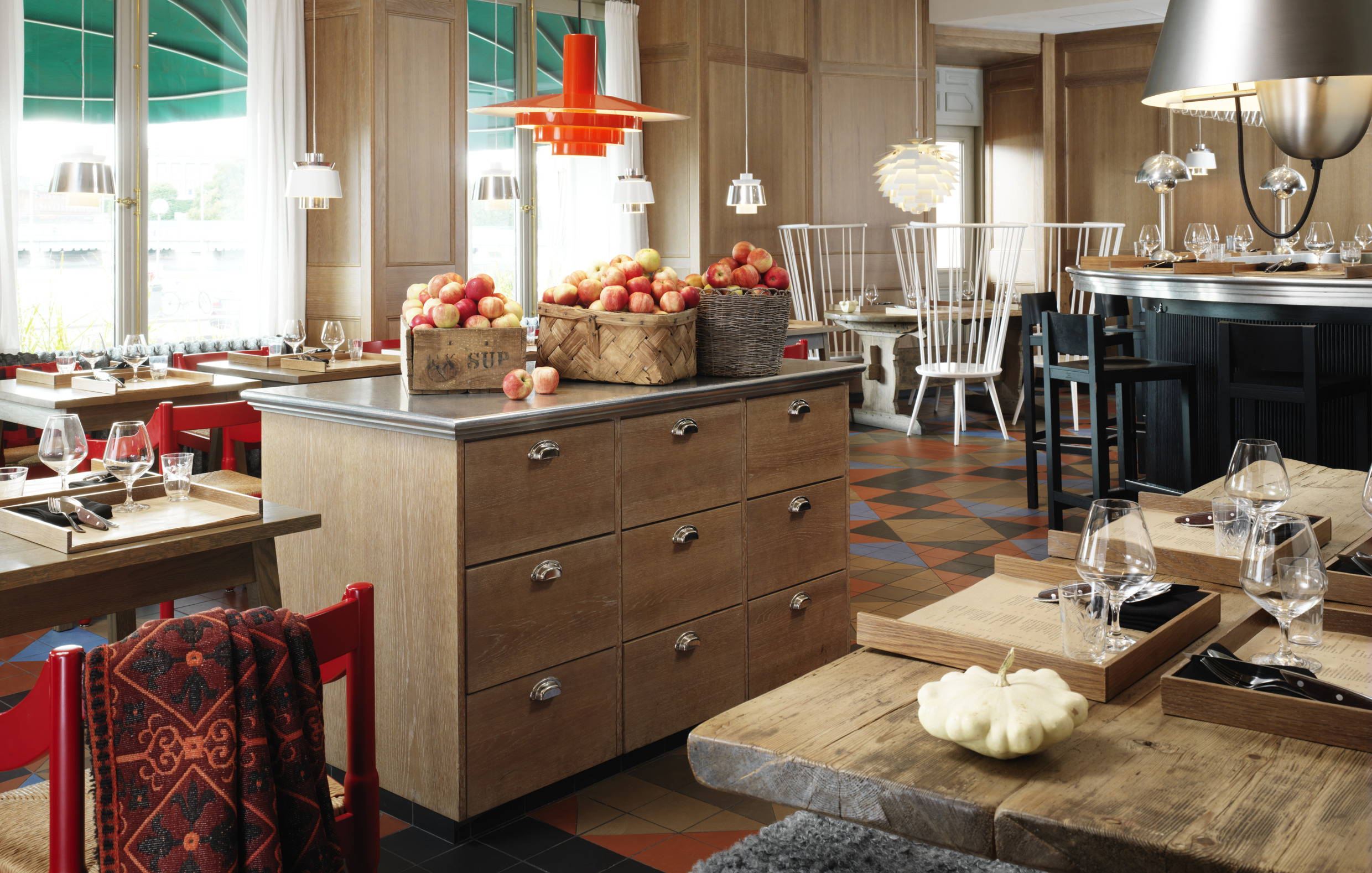 Een warme en stijlvolle eetruimte in Matbaren in Stockholm, met rustieke houten tafels, Scandinavische designelementen en een seizoensgebonden inrichting met verse appels.