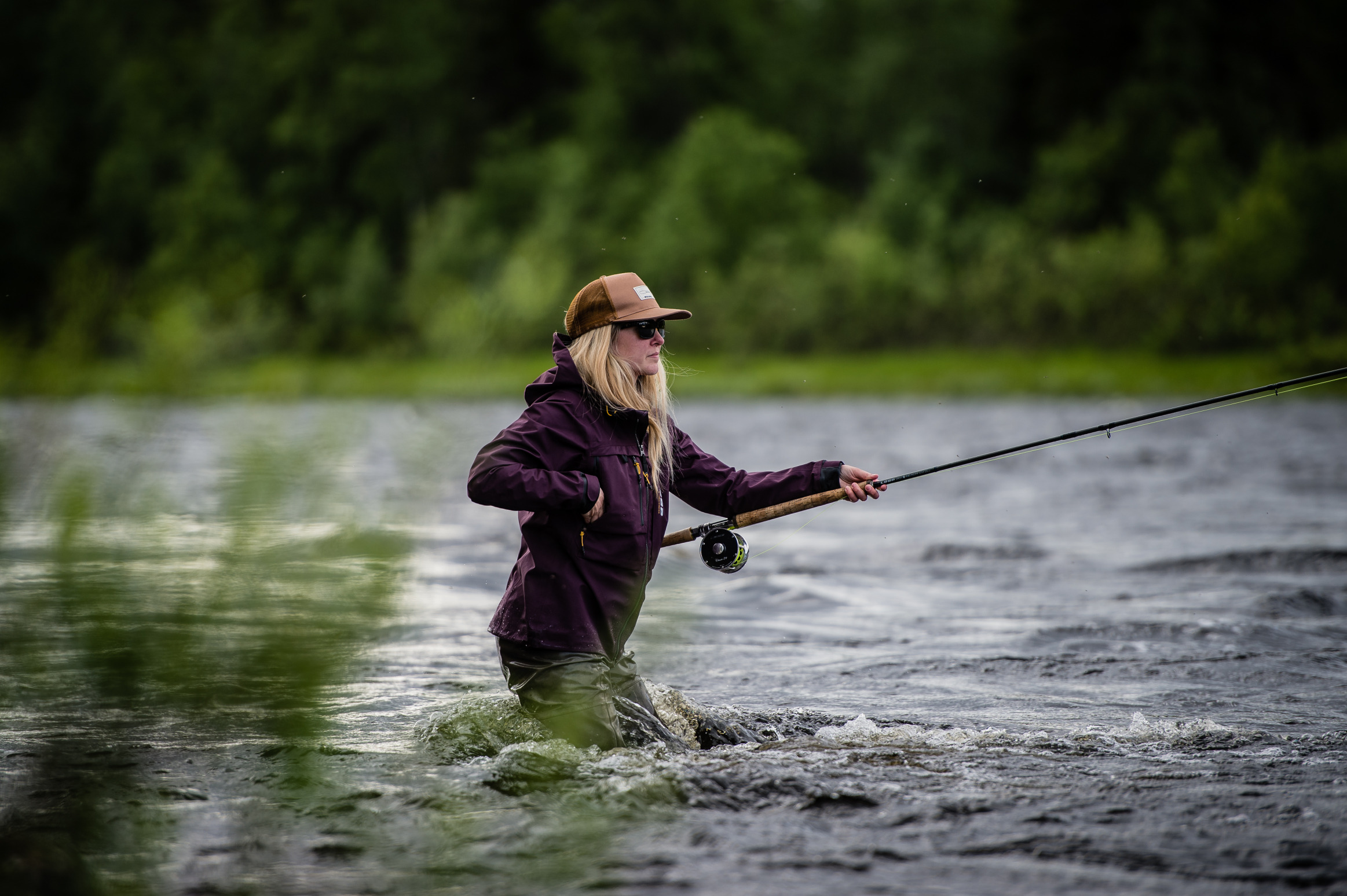 Een meisje is aan het vliegvissen in een rivier.