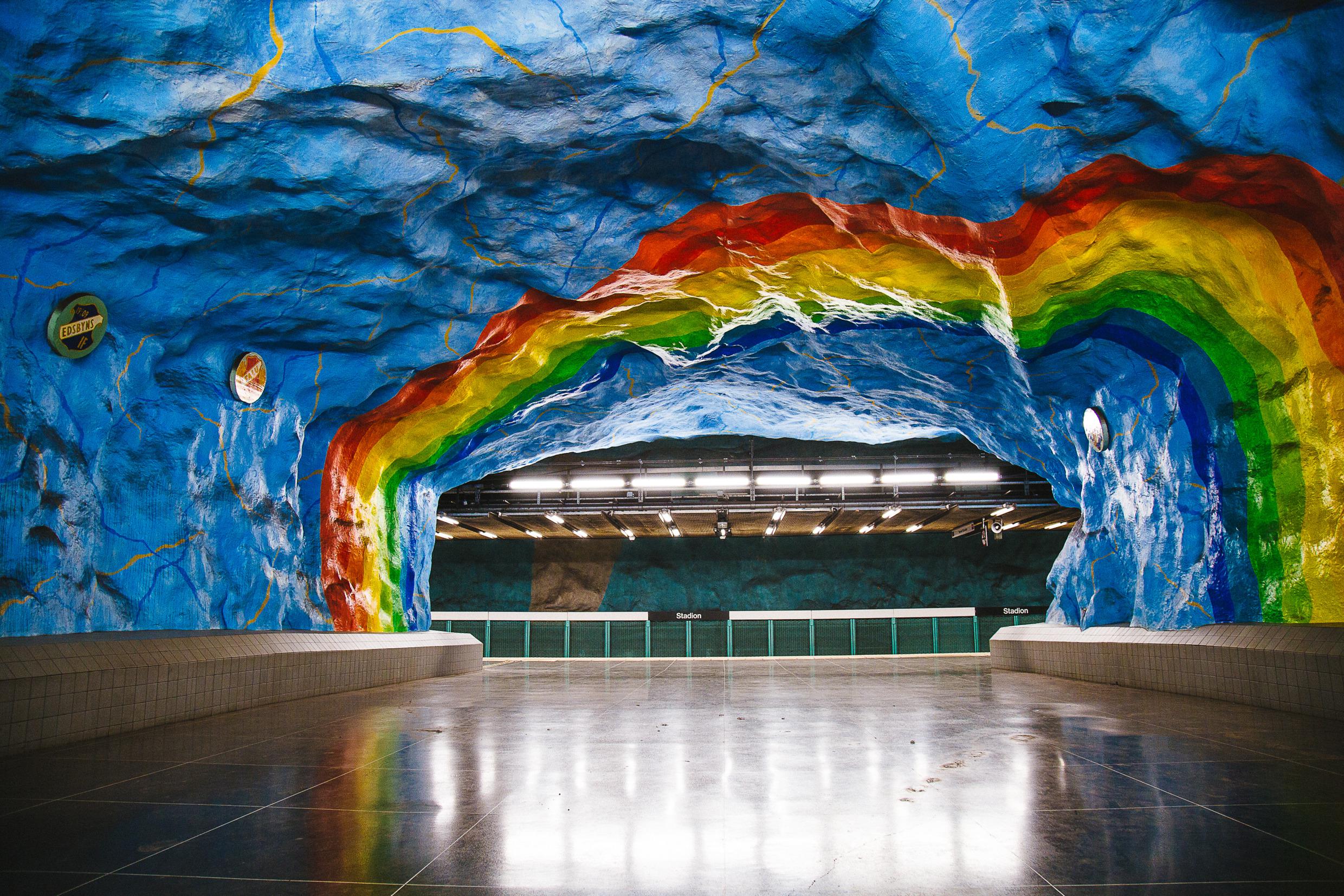 Eine U-Bahn Station in Stockholm die von Künstlern gestaltet wurde. Ein riesiger gemalter Regenbogen schmückt die Wand.