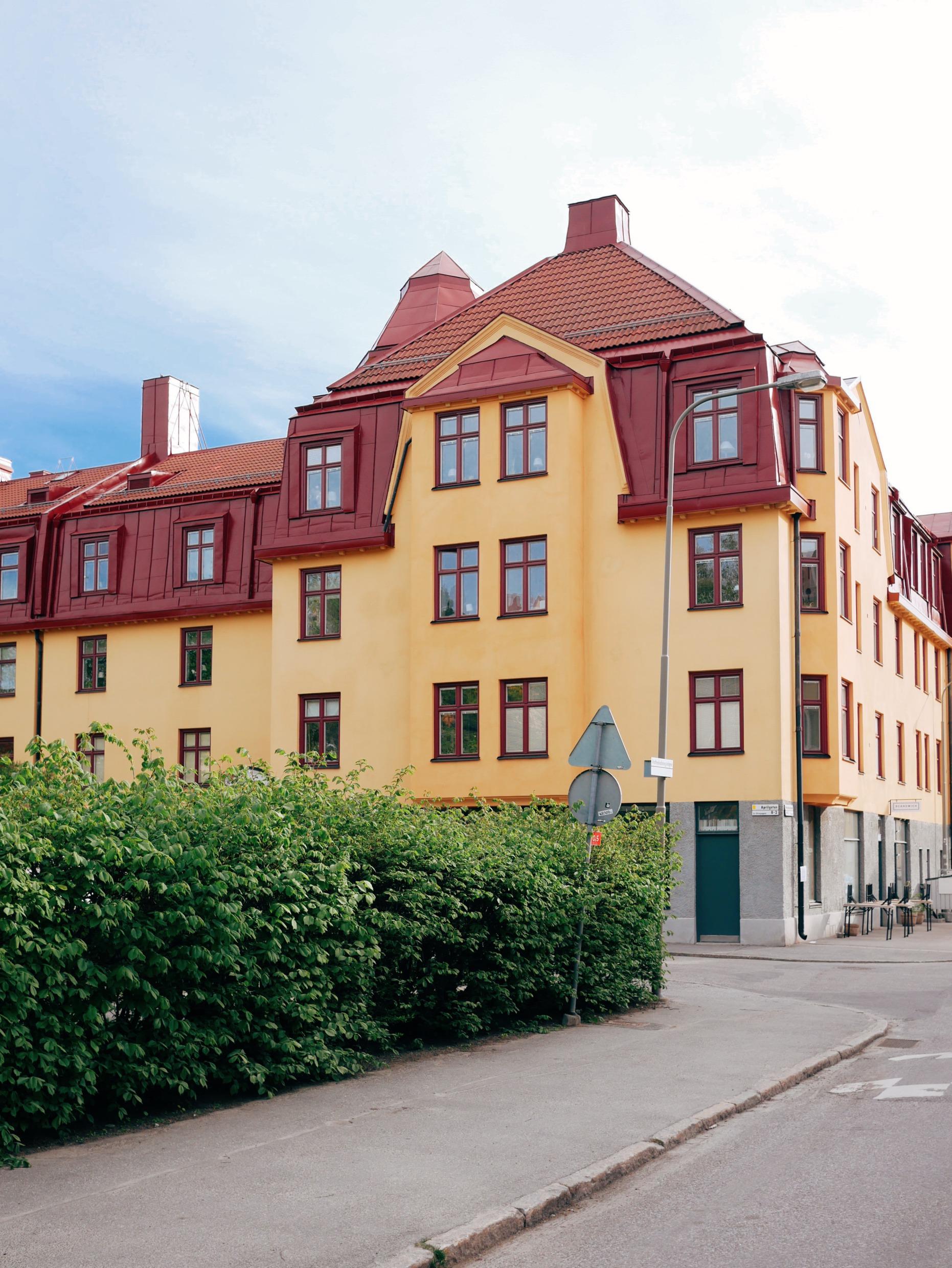 Ein altes gelbes Steinhaus mit rotem Dach auf einer Straße in einem Vorort.