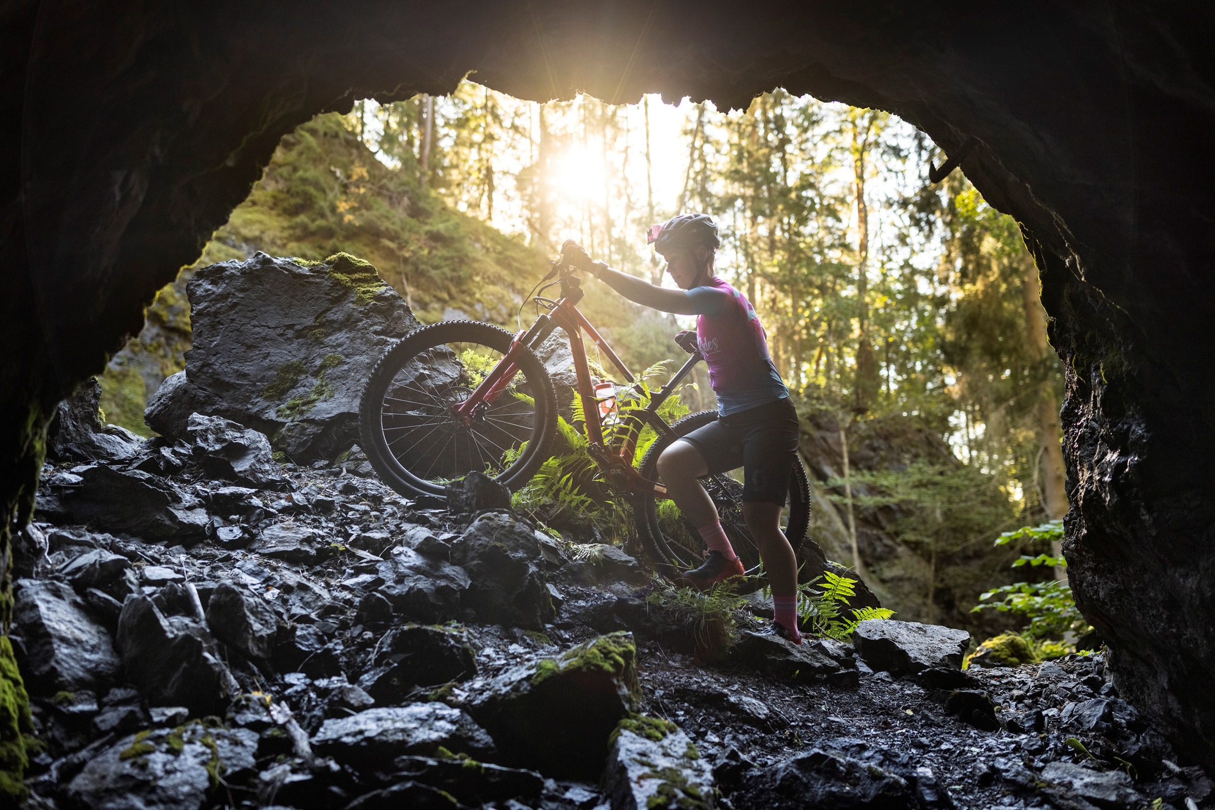 Iemand die zijn fiets een rotsachtige helling opduwt.