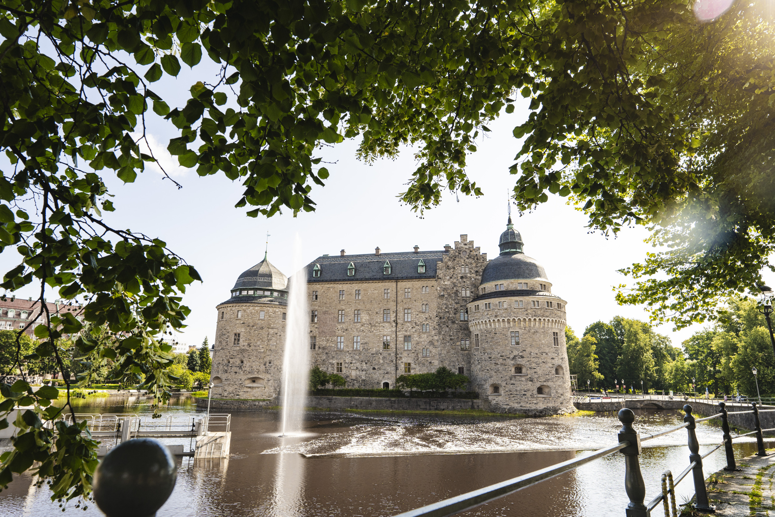 Un château médiéval entouré d'une rivière et d'arbres verdoyants.