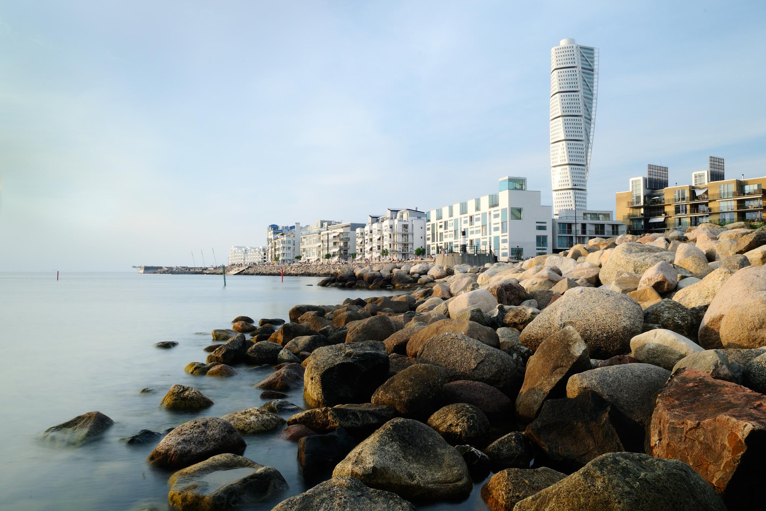 Vue sur la ville de Malmö avec notamment l'océan, une jetée en béton, des immeubles et le gratte-ciel Turning Torso.