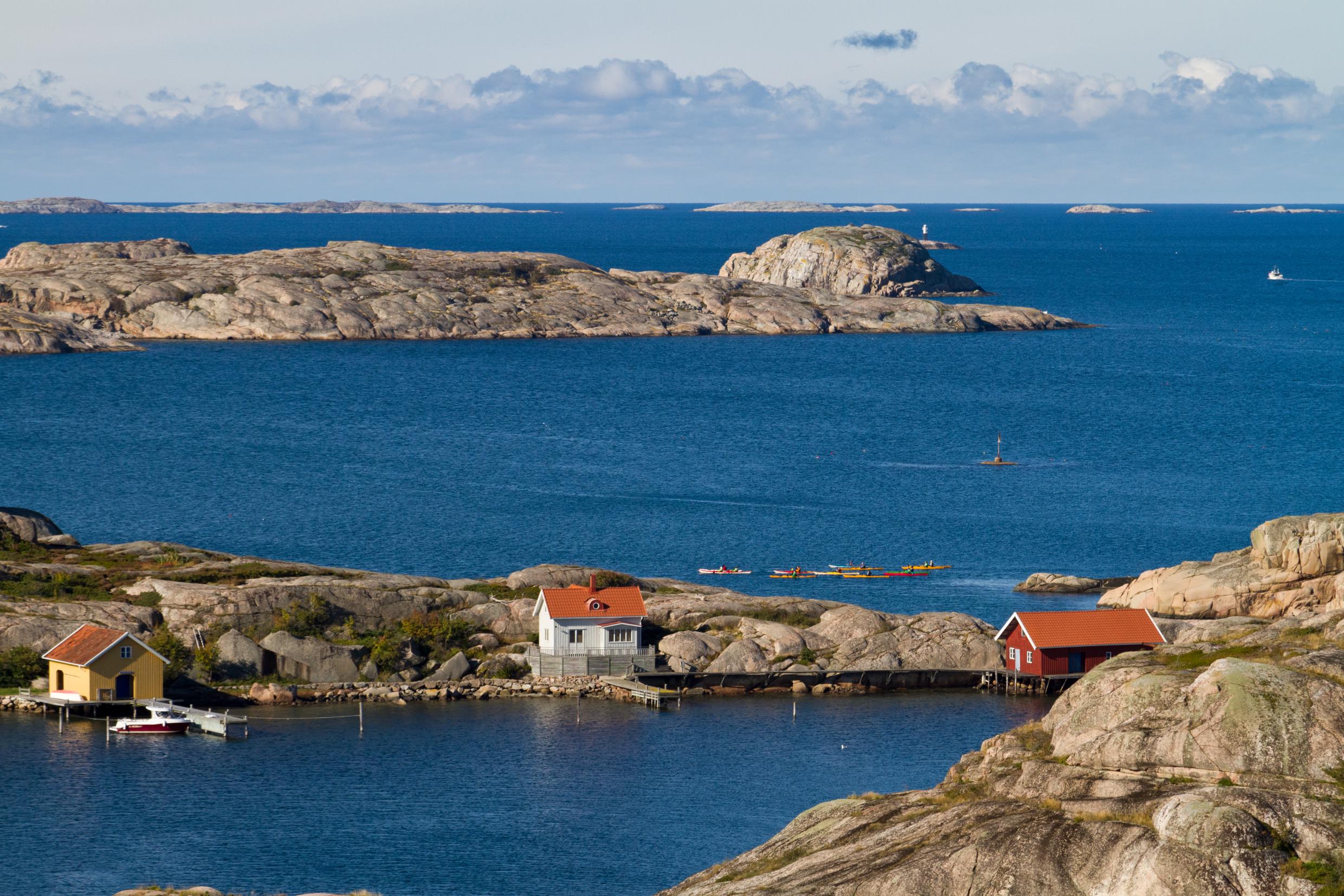 A small house and two boat houses on a rocky island on the west coast.