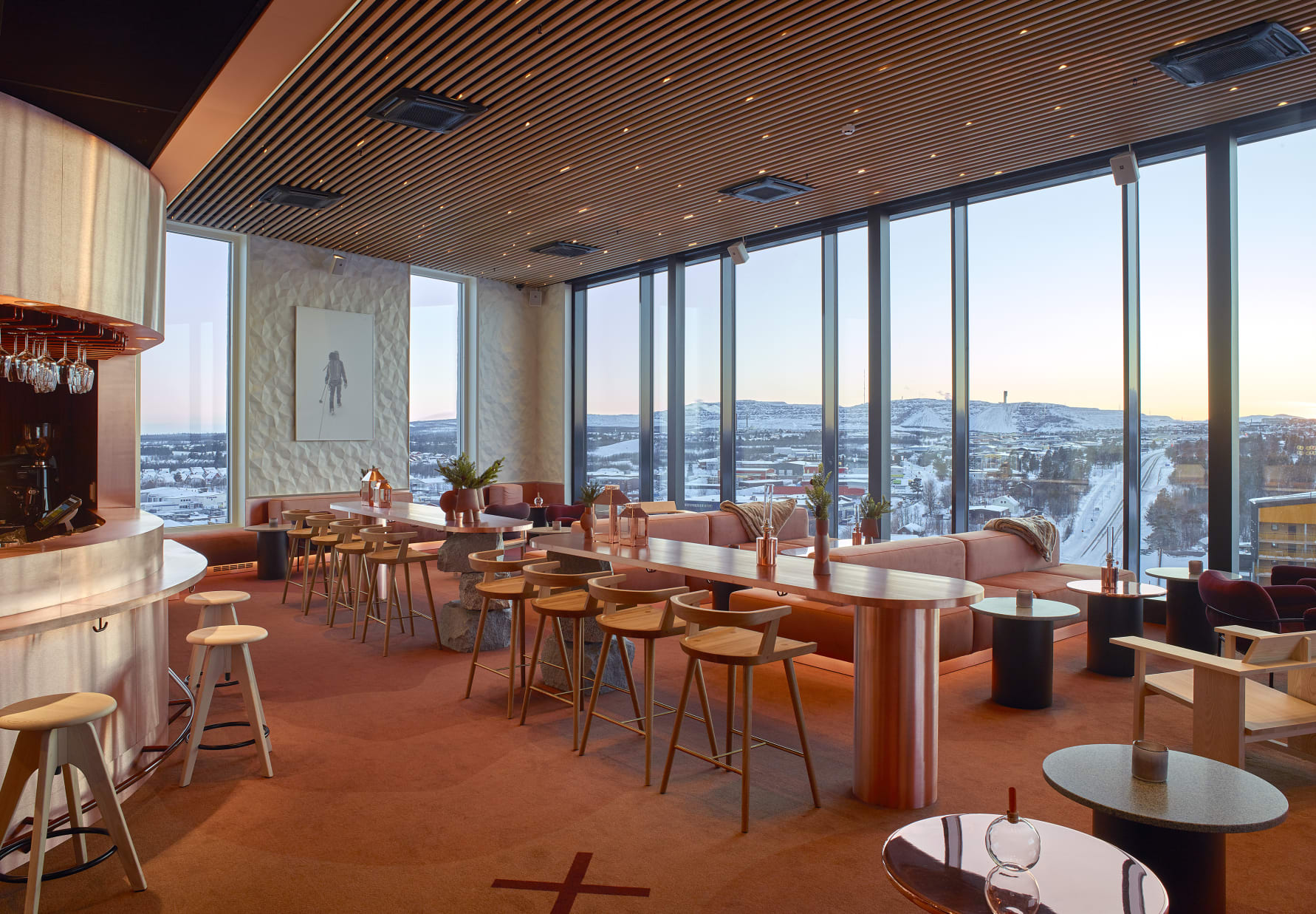 Het interieur van de skybar in Scandic Kiruna, met grote ramen die uitkijken over de besneeuwde stad en het arctische landschap.