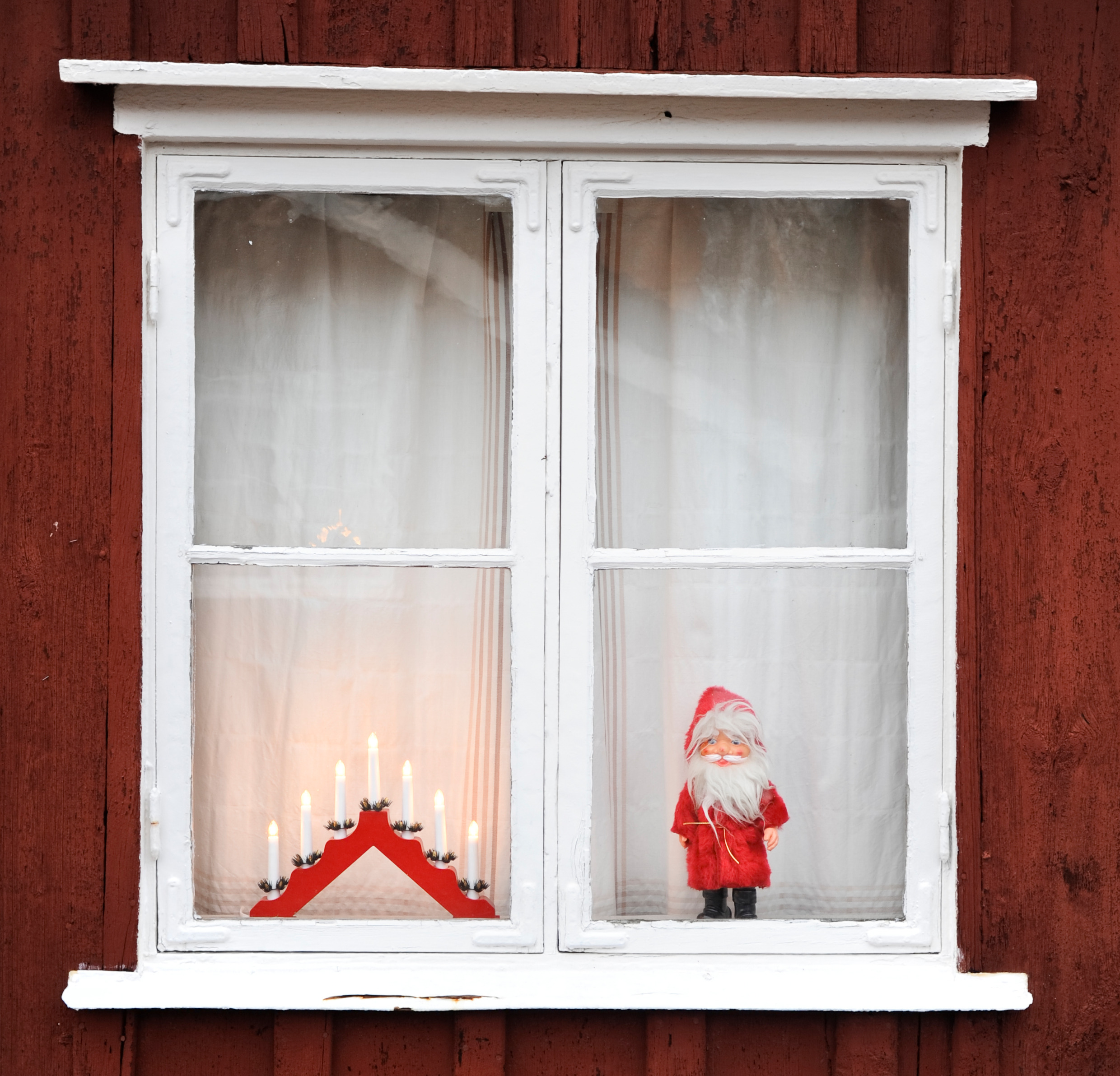 Ein Fenster von außen gesehen, geschmückt mit einem Weihnachtsleuchter und einer Weihnachtsmannpuppe.