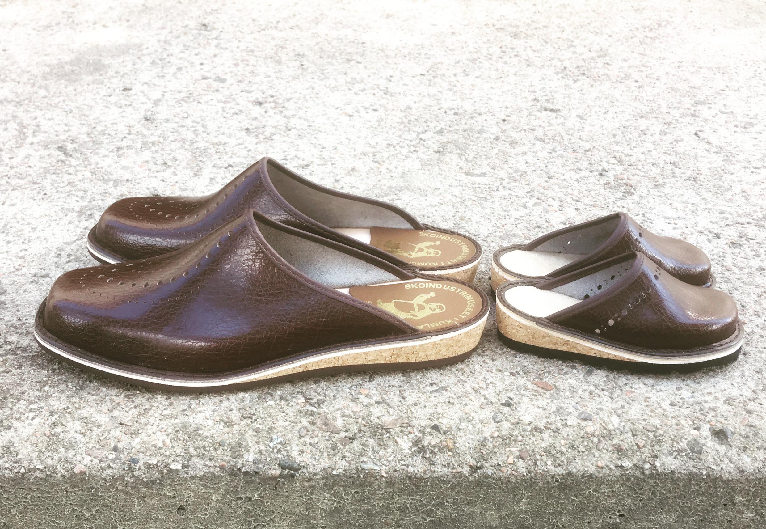 Close-up at two pair of brown slippers. One pair is a large size for an adult and the other is a small size for a child.