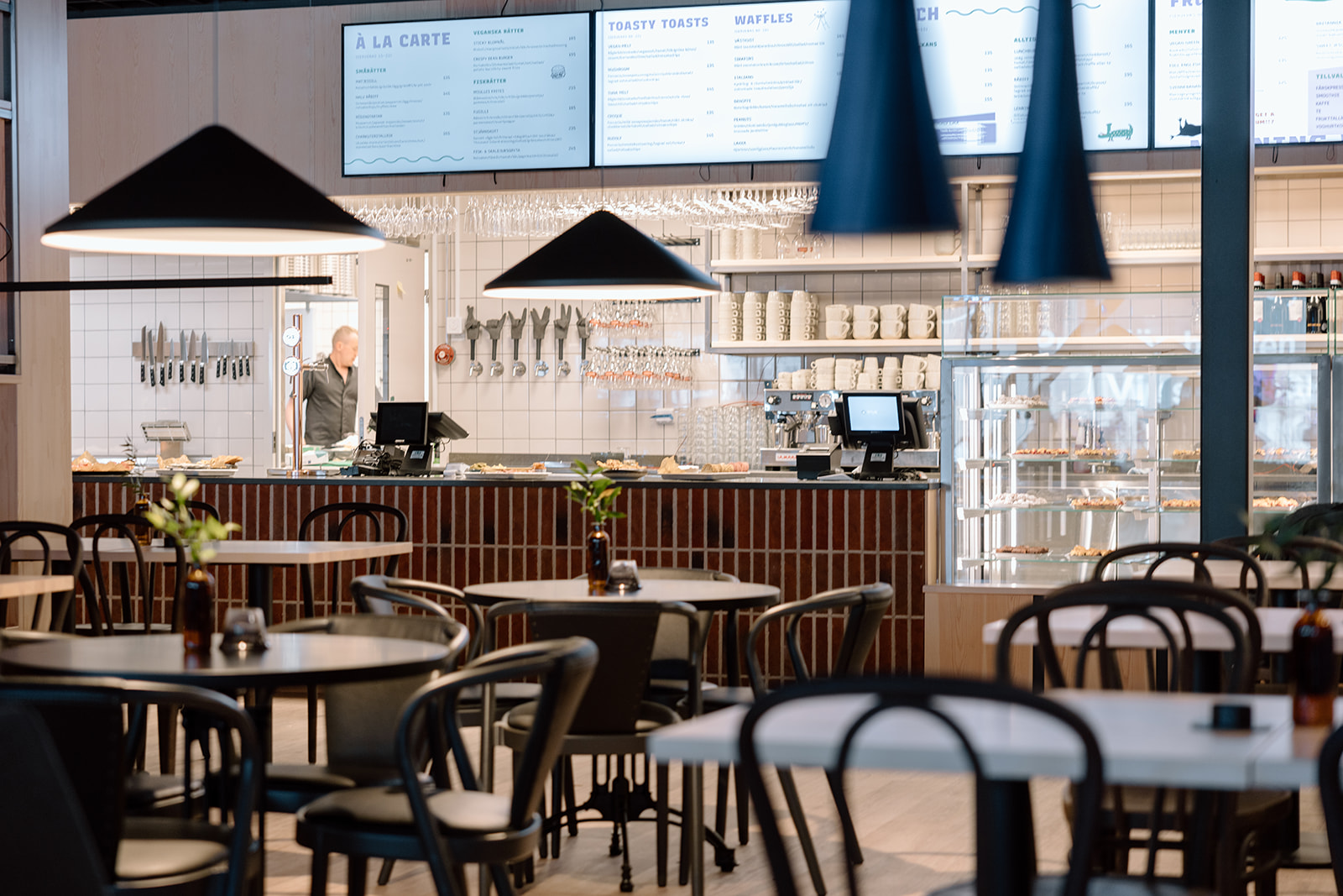 Interior of a modern restaurant in Kiruna with tables, chairs and an open counter with menu boards.