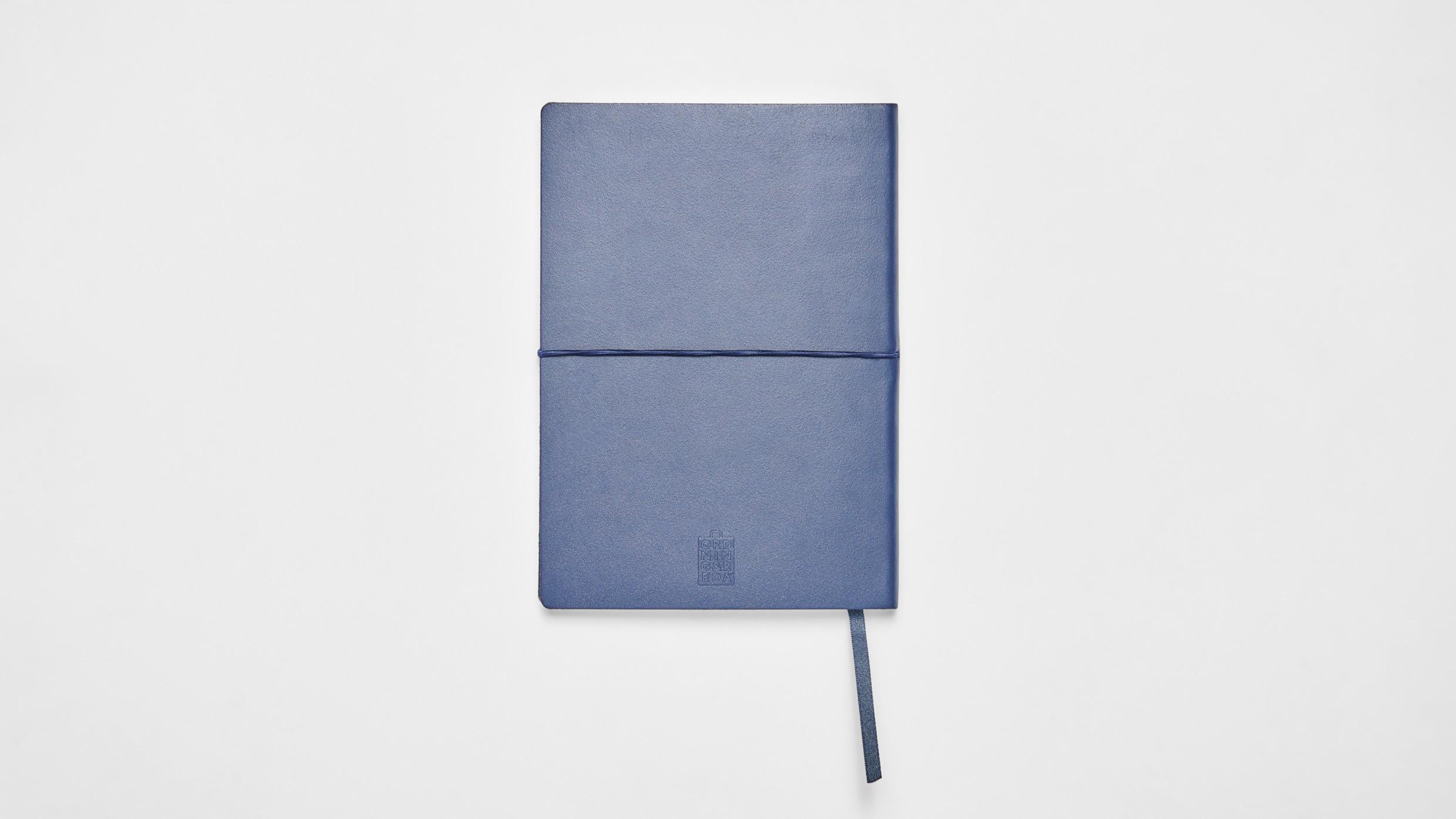 Een blauwe notitieblok op een wit oppervlak.