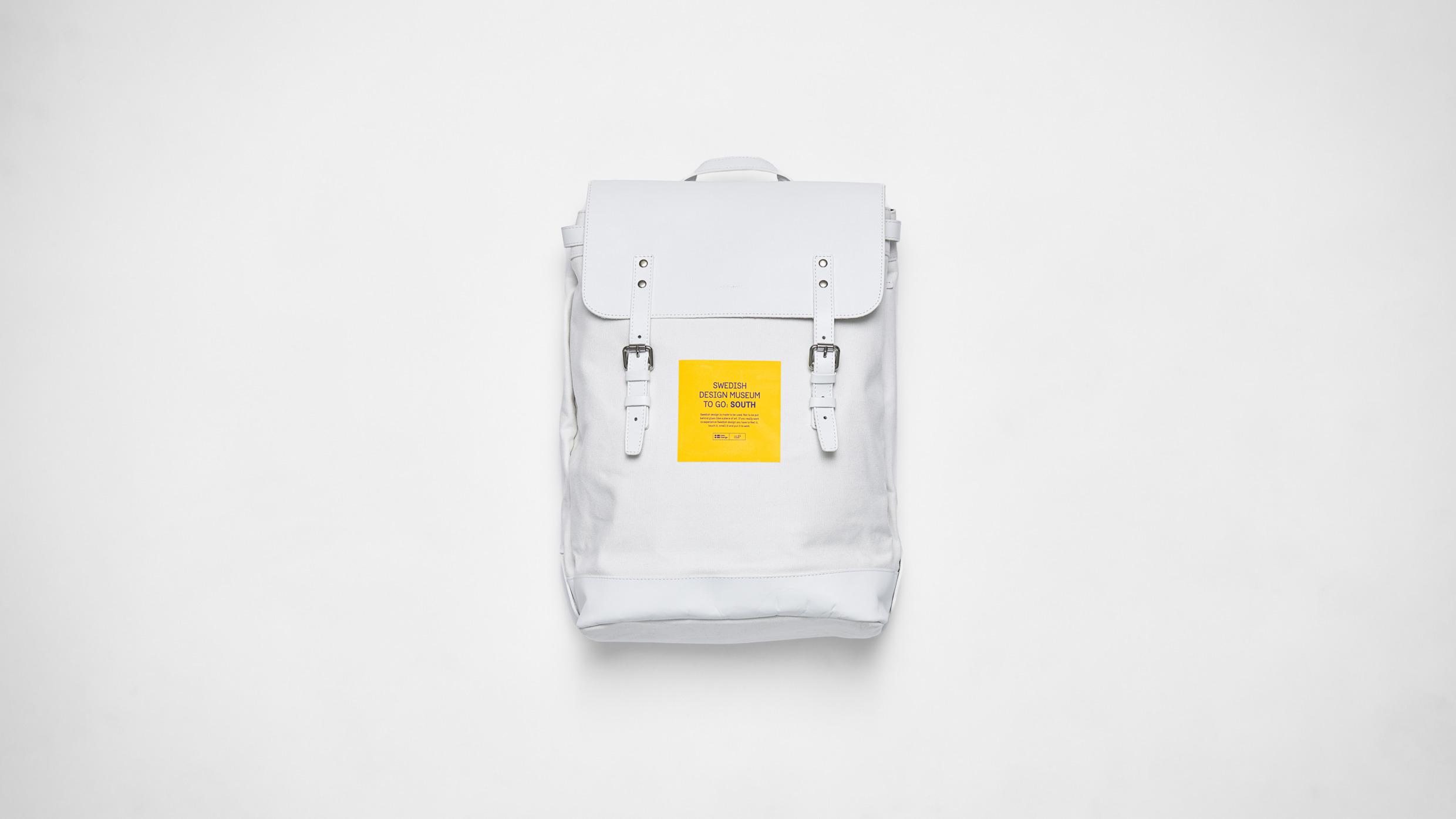 Een witte rugzak met een gele sticker erop.