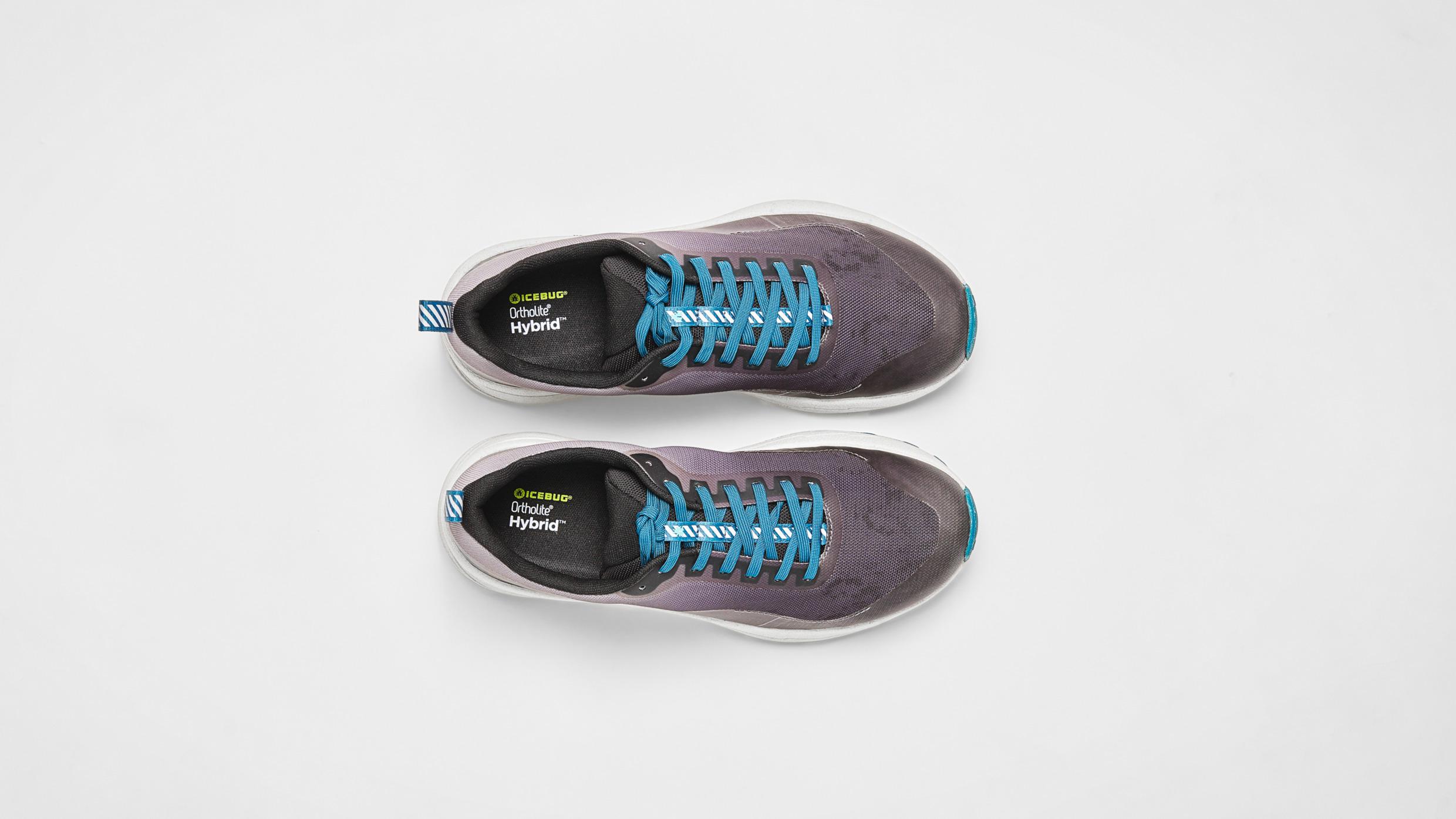 Grijze schoenen met blauwe veters op een witte ondergrond.