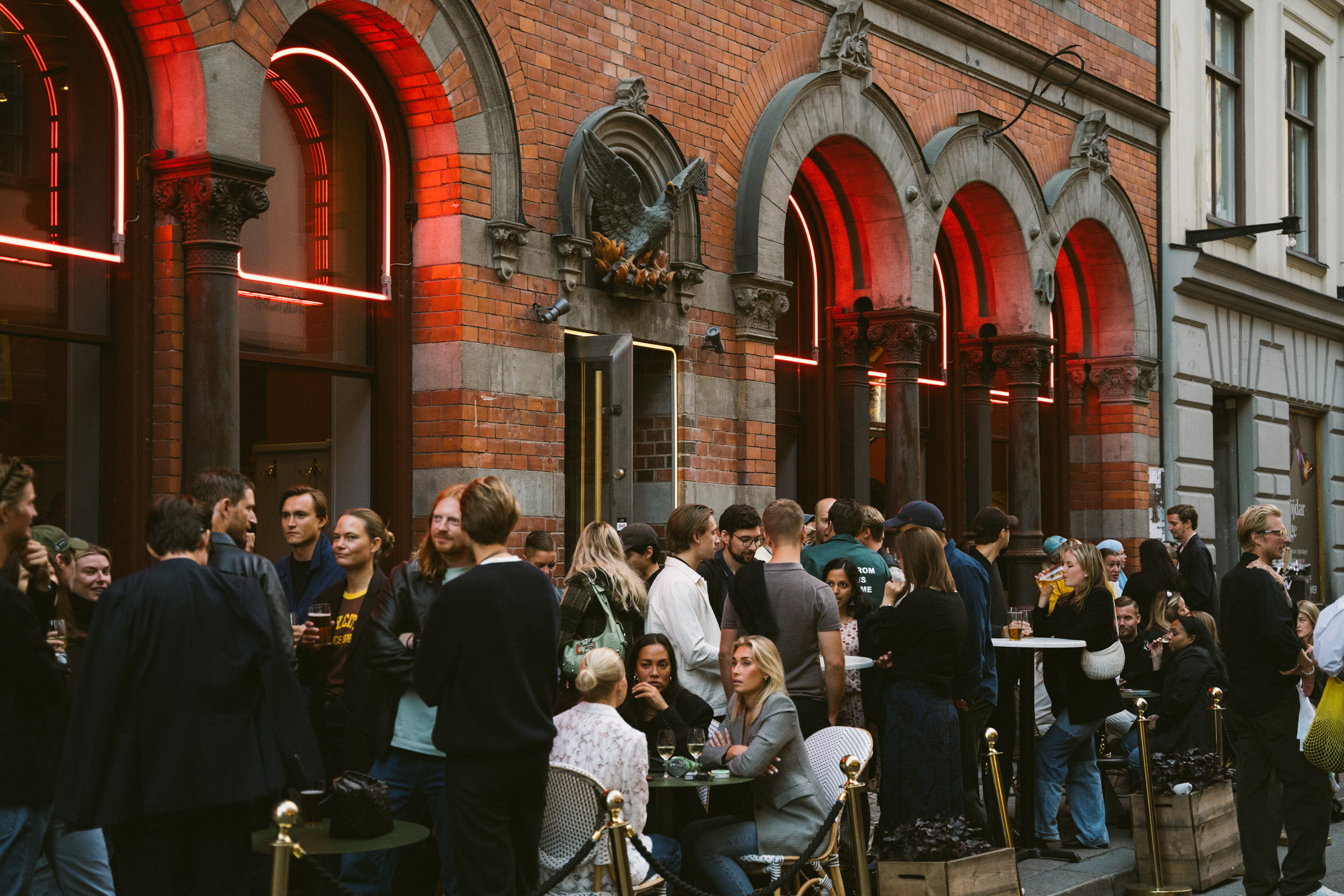Crowds enjoying a lively evening sitting outside Riche Fenix in Södermalm, Stockholm.