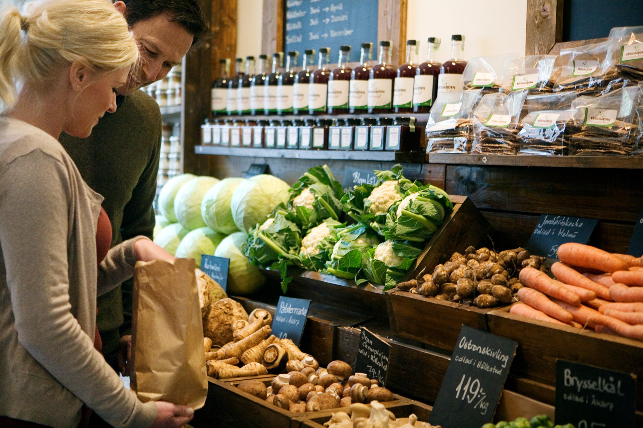 A man and woman are in a grocery store picking out vegetables.