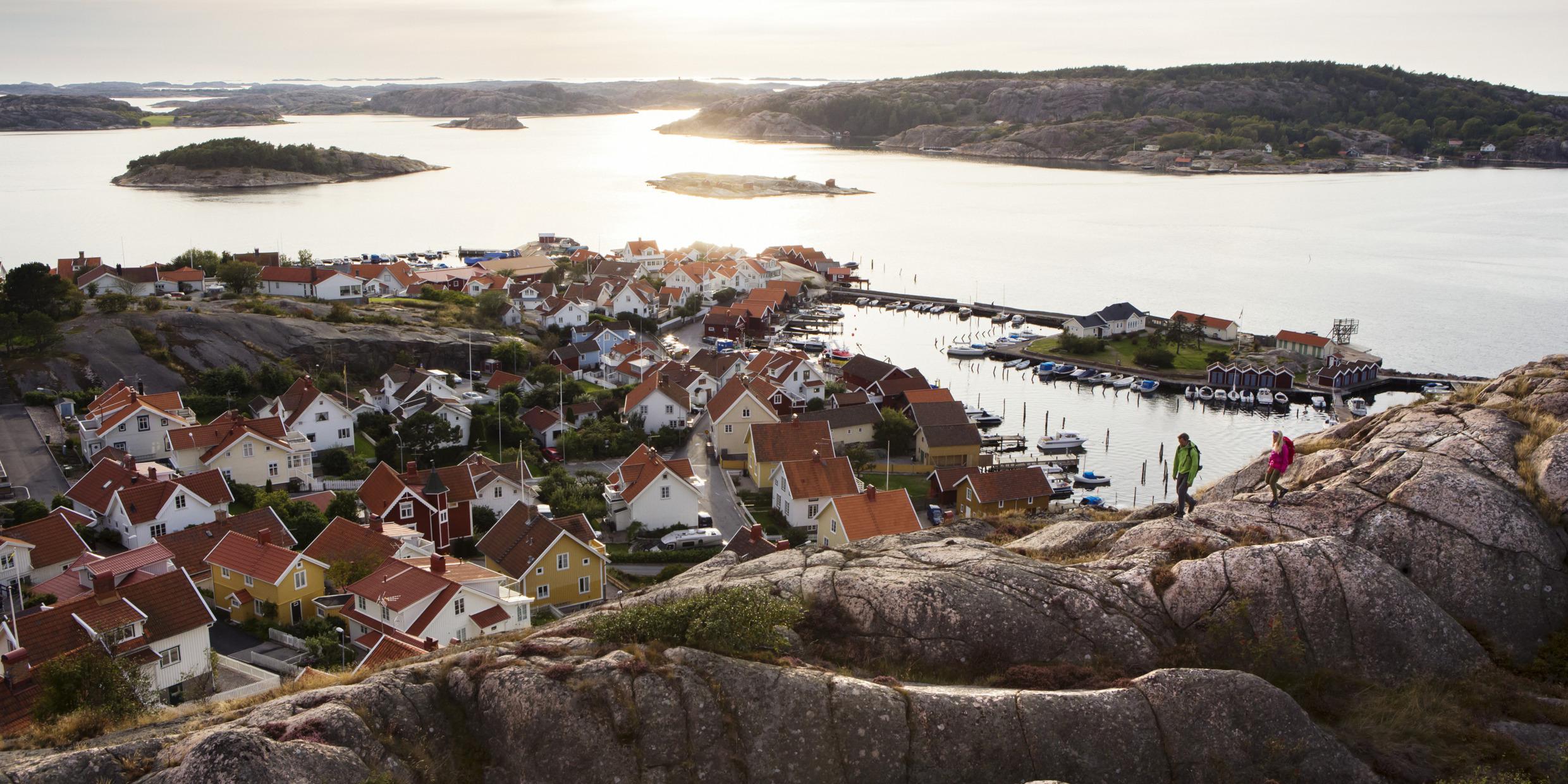 Two people are hiking along the hills above Fjällbacka and the west coast archipelago in the background.