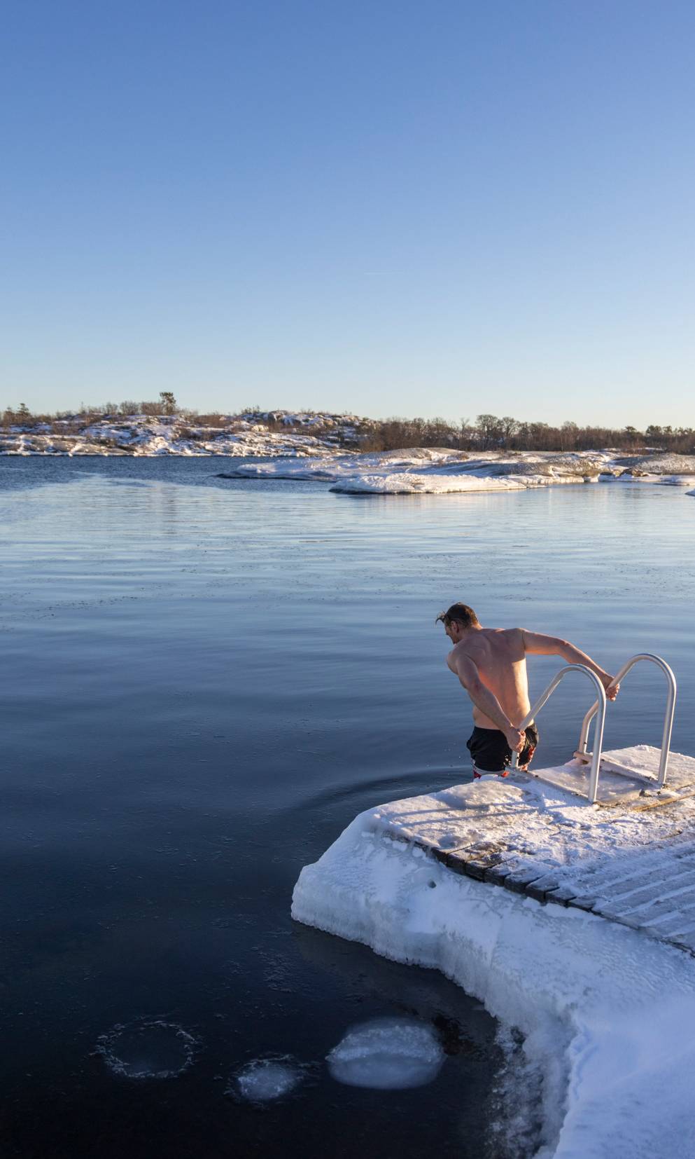 A person ice bathing on a sunny winter day.